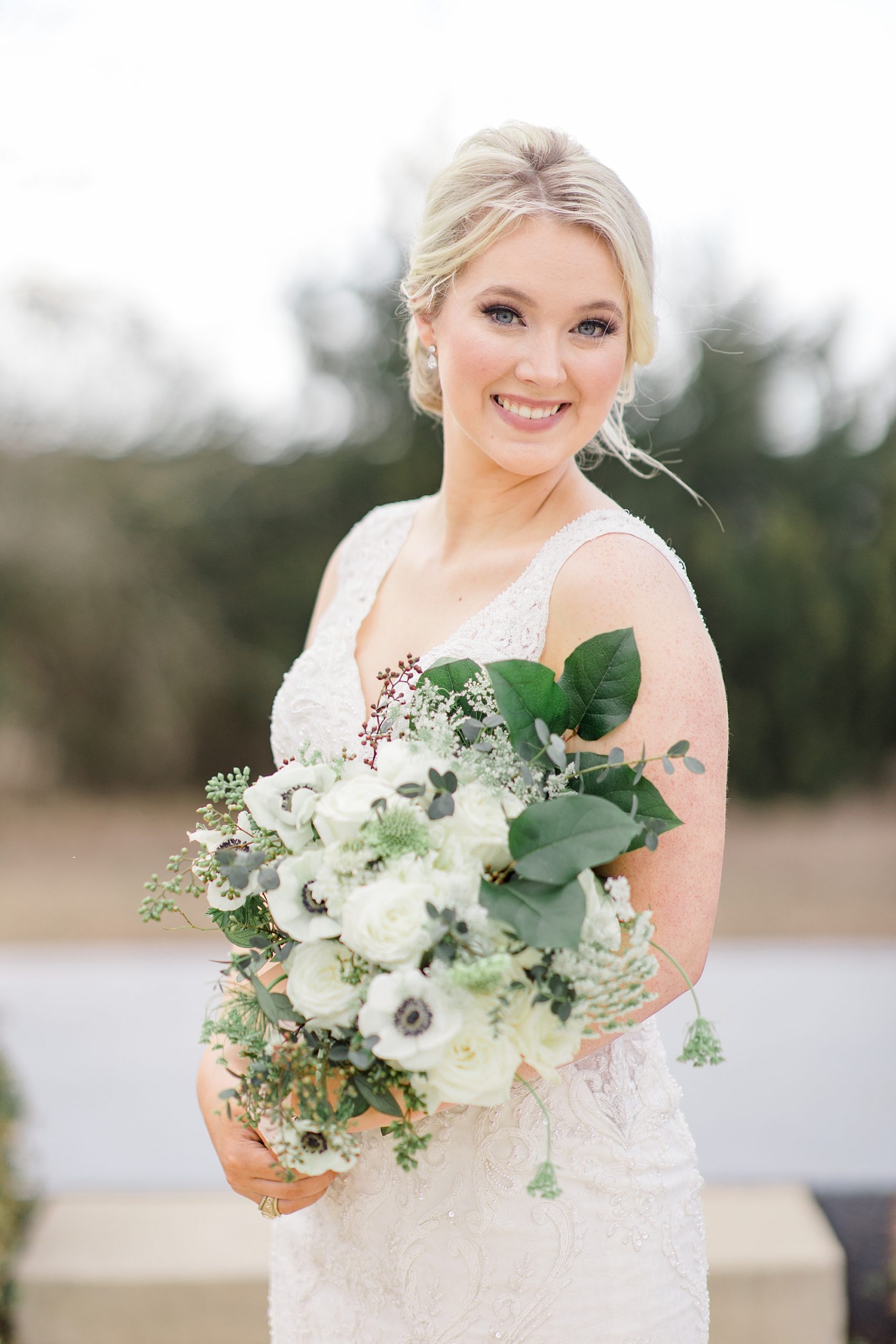bride smiles down at bouquet in Dallas TX