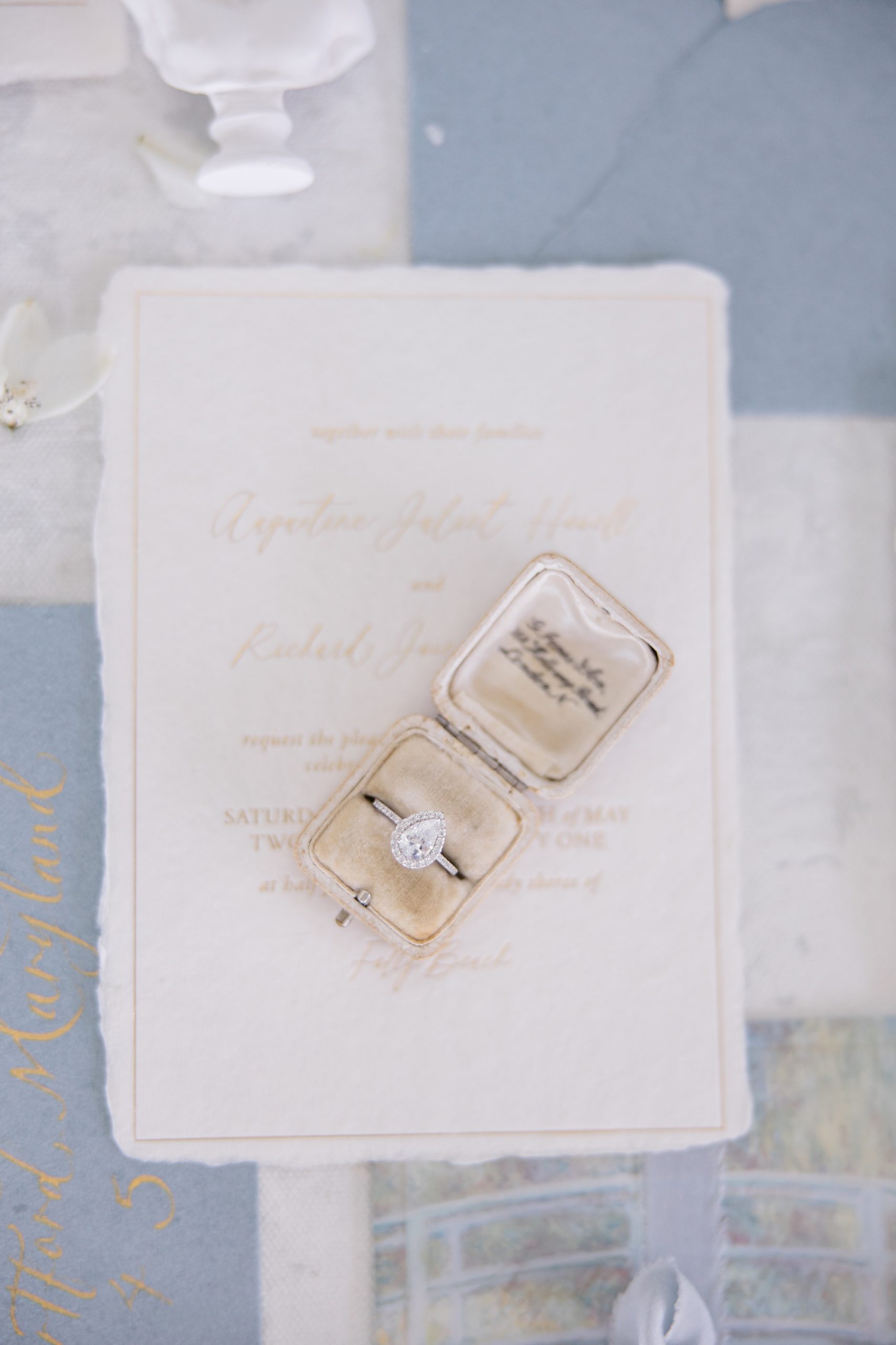 rings in champagne colored ring box lay on watercolor wedding invitations 