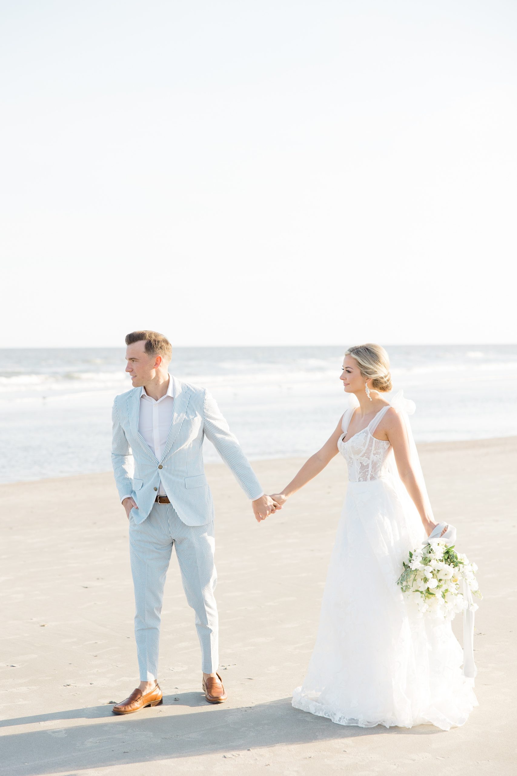 groom leads bride across Folly Beach on wedding day
