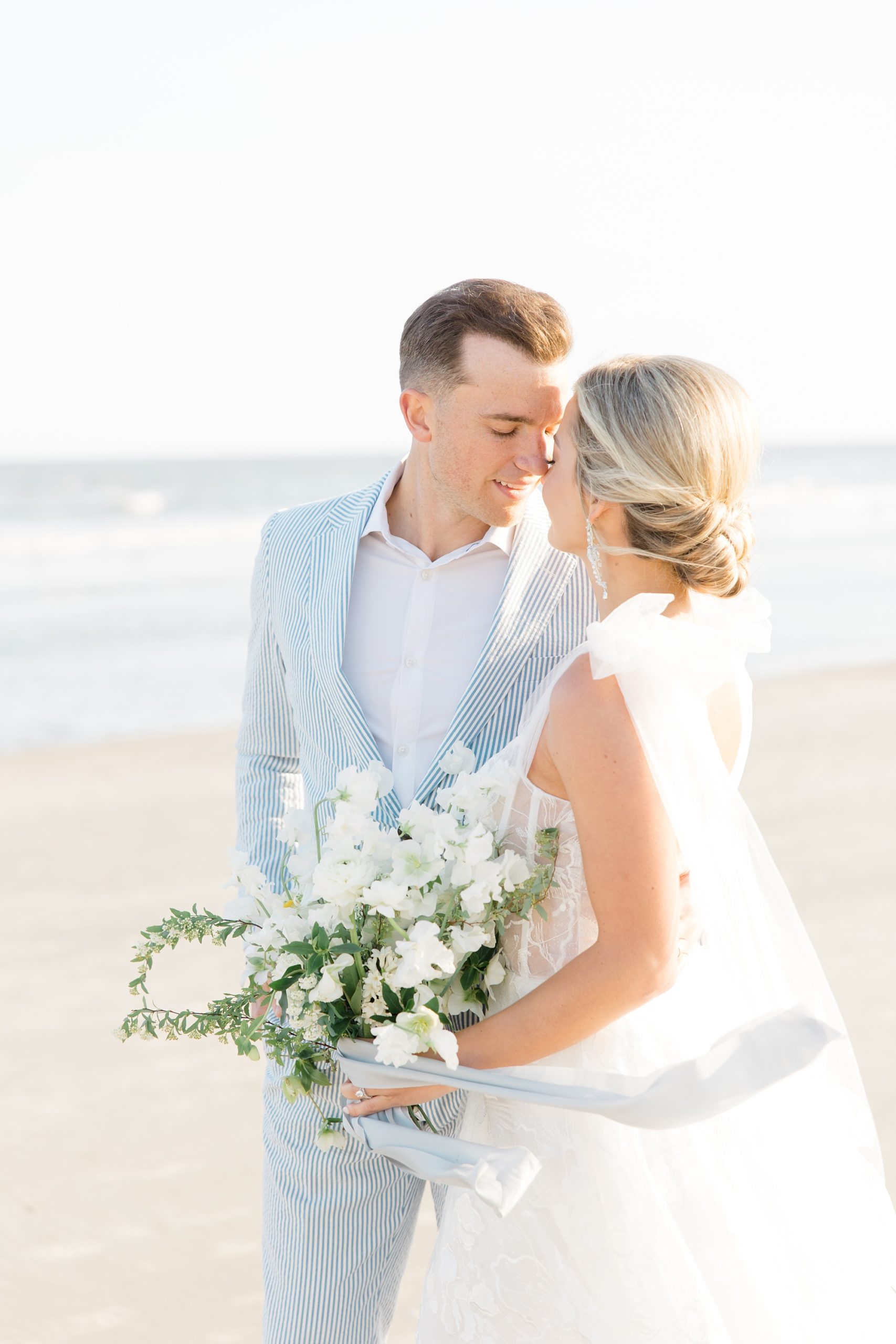 bride and groom stand with noses touching during portraits at Folly Beach