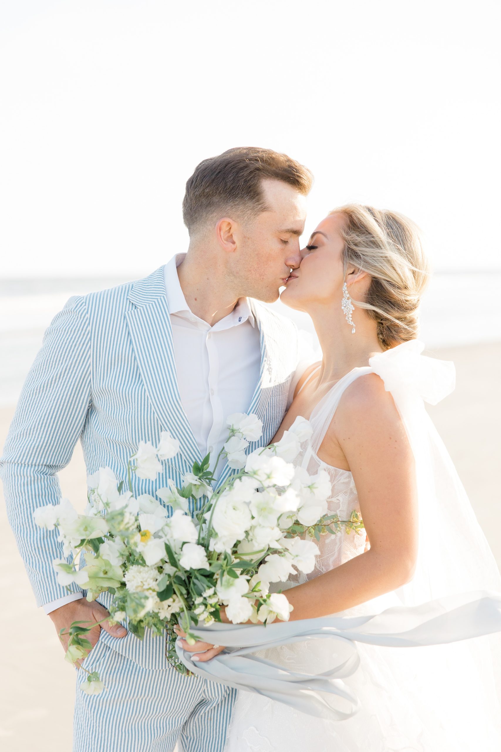 couple kisses on Folly Beach during wedding portraits in the wind