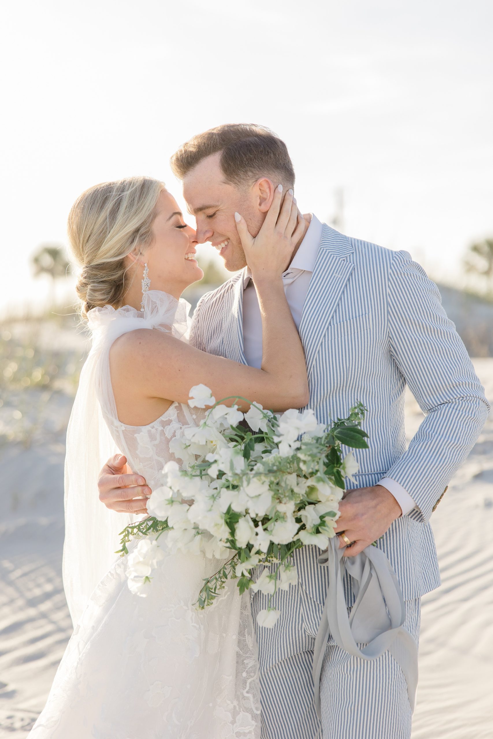 bride and groom stand touching noses on Folly Beach
