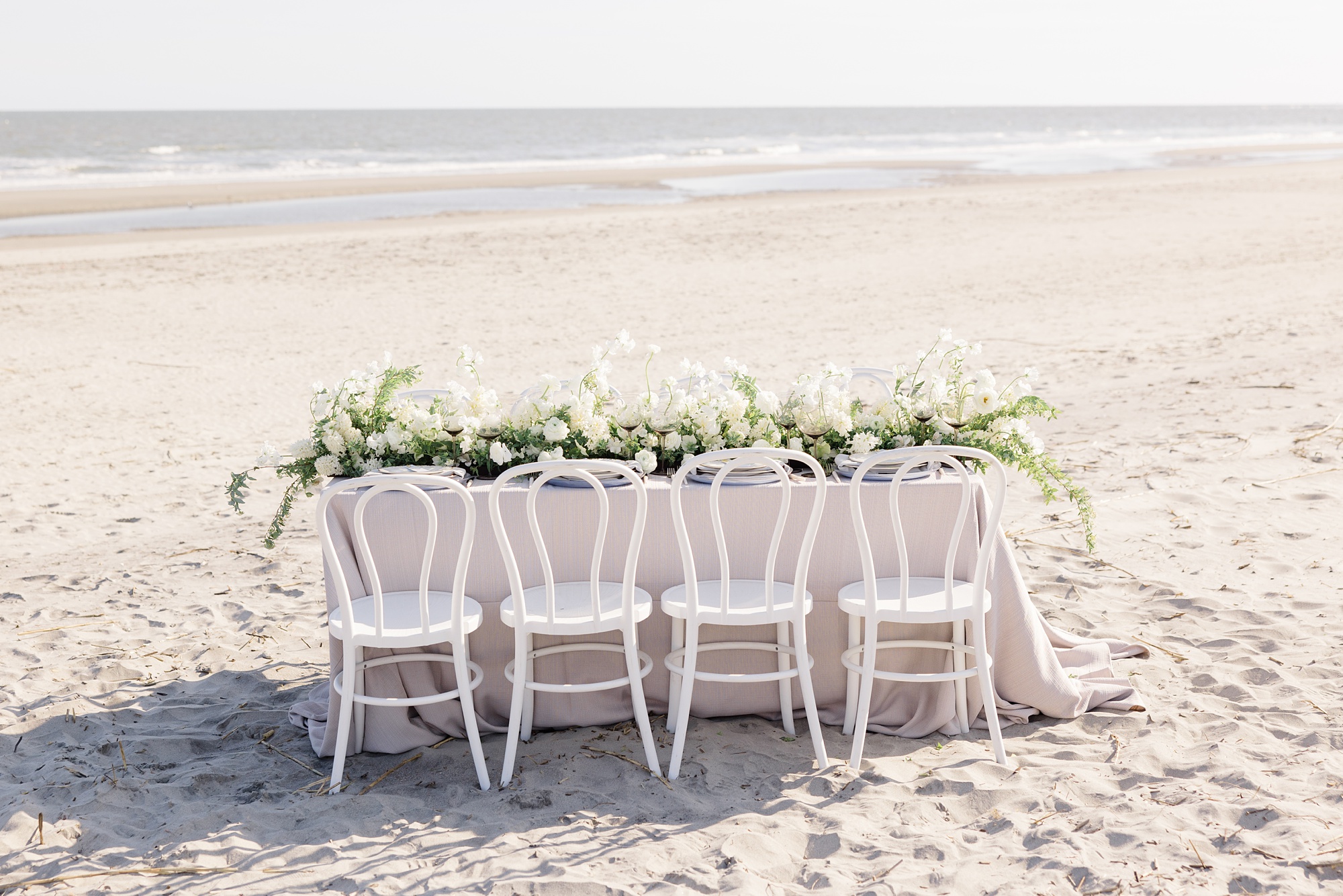 wedding reception on the beach with white chairs 