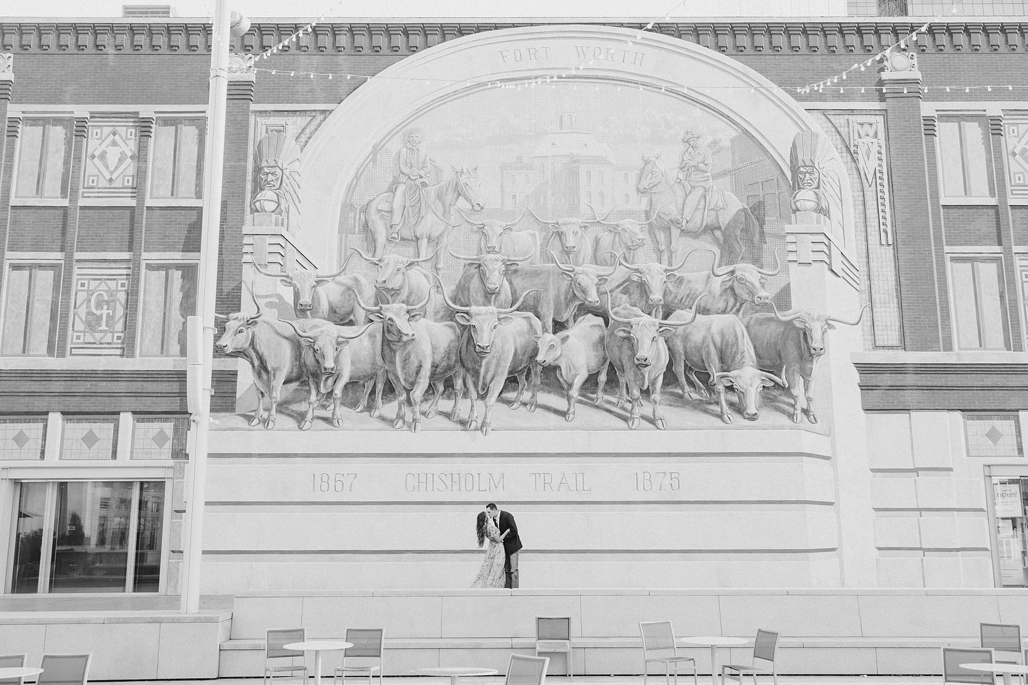engage couple kisses under Chisholm Trail mural