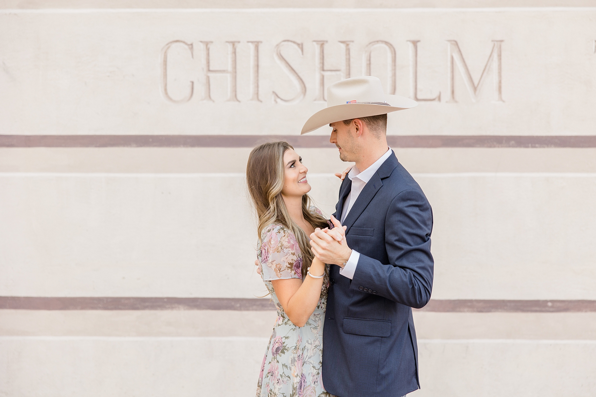 engaged couple dances by Chisholm Trail mural
