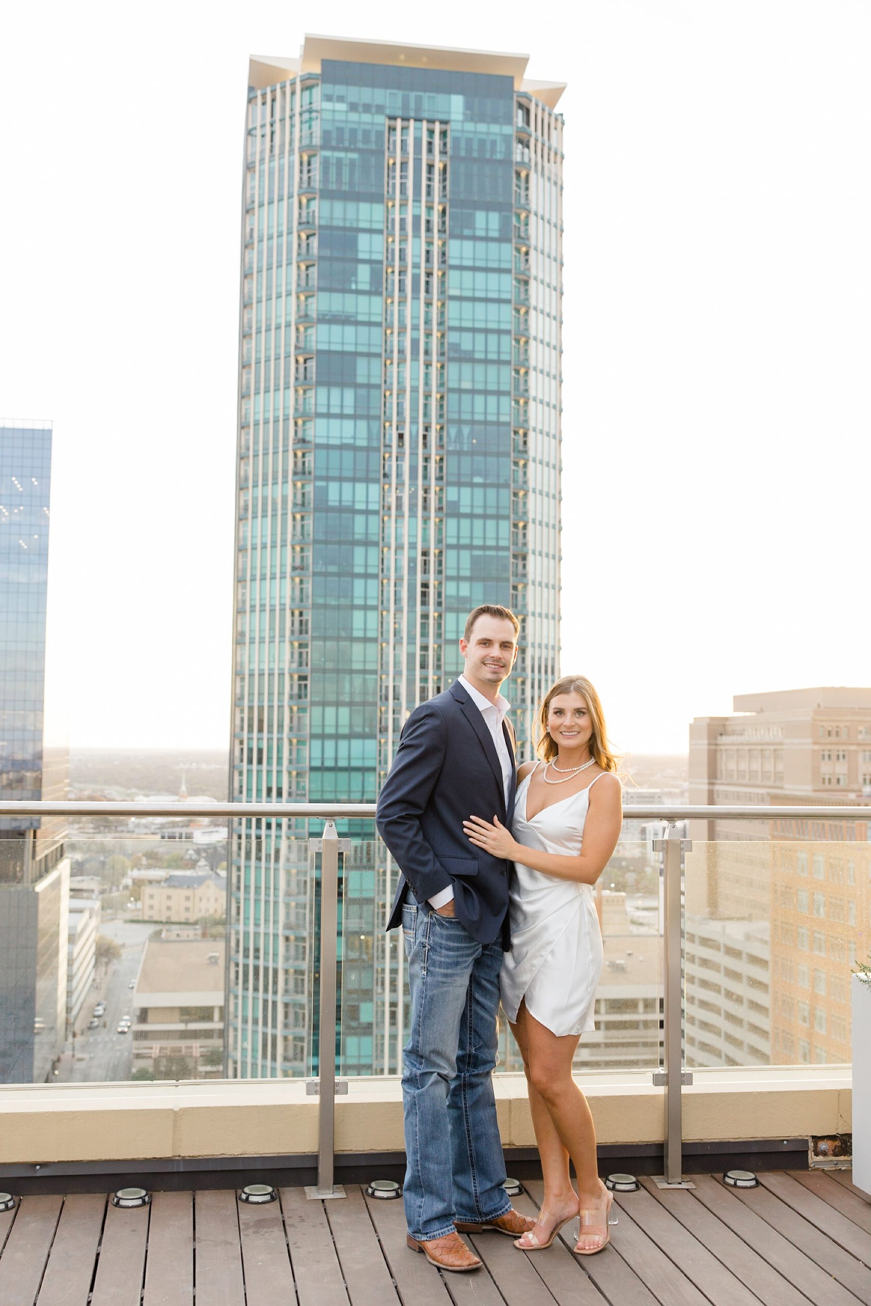 engaged couple poses on rooftop in Fort Worth