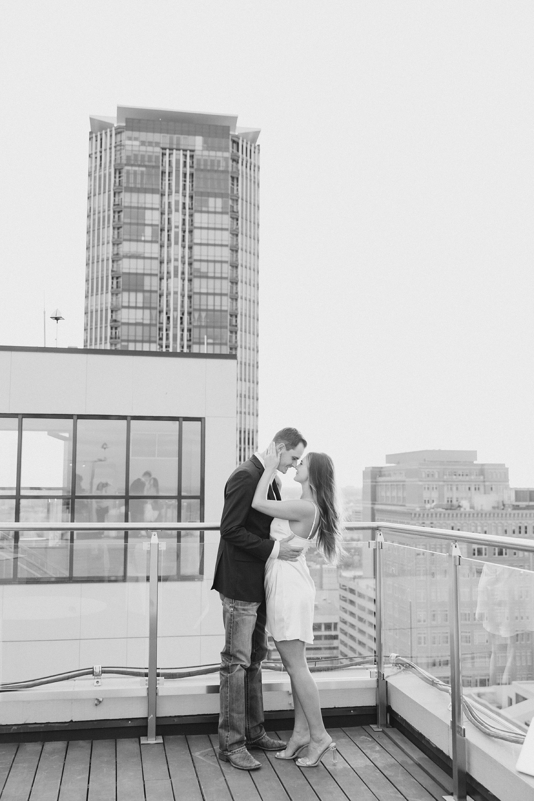 engaged couple kisses during photos on rooftop in Fort Worth