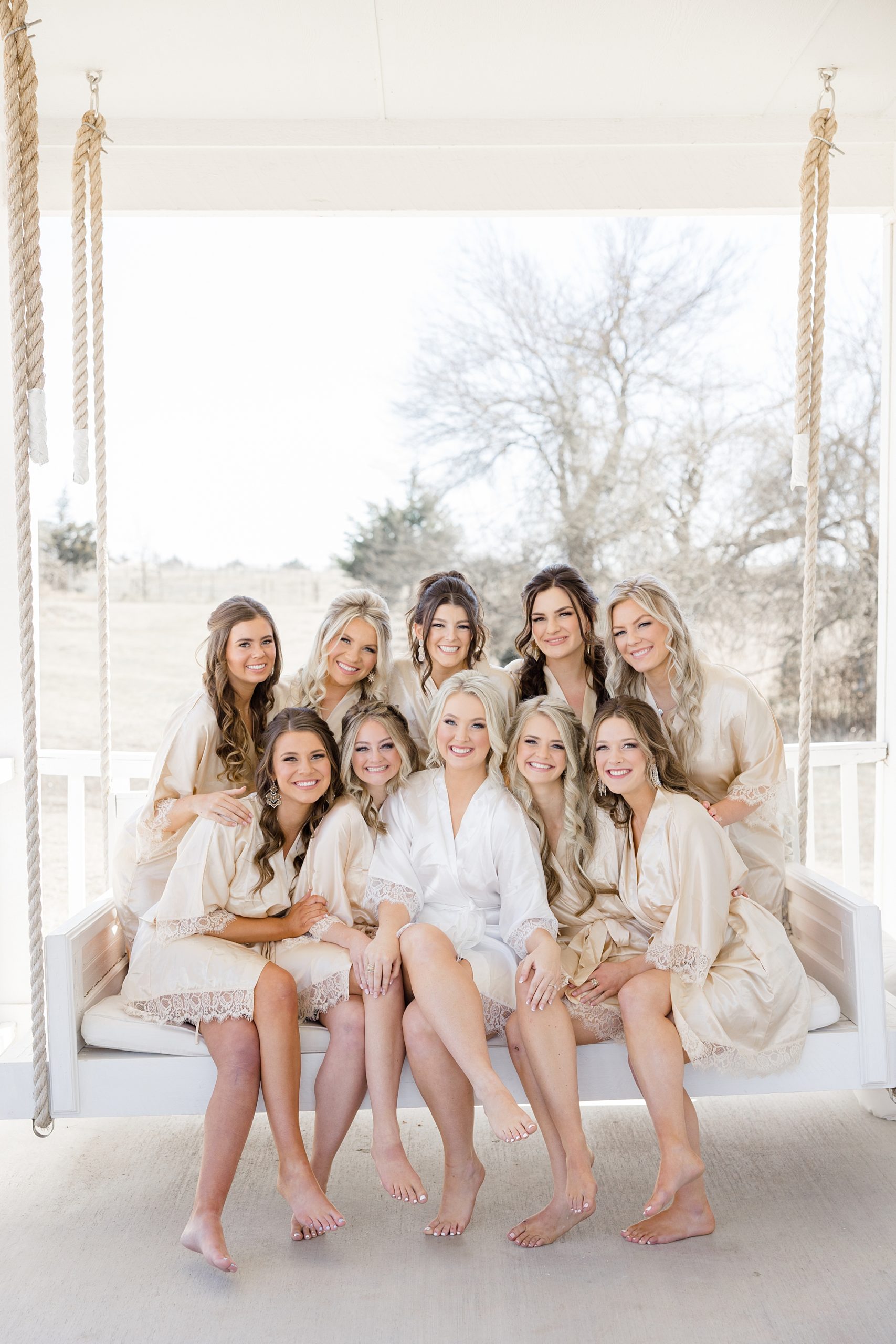 bride and bridesmaids sit on swing at The Grand Ivory