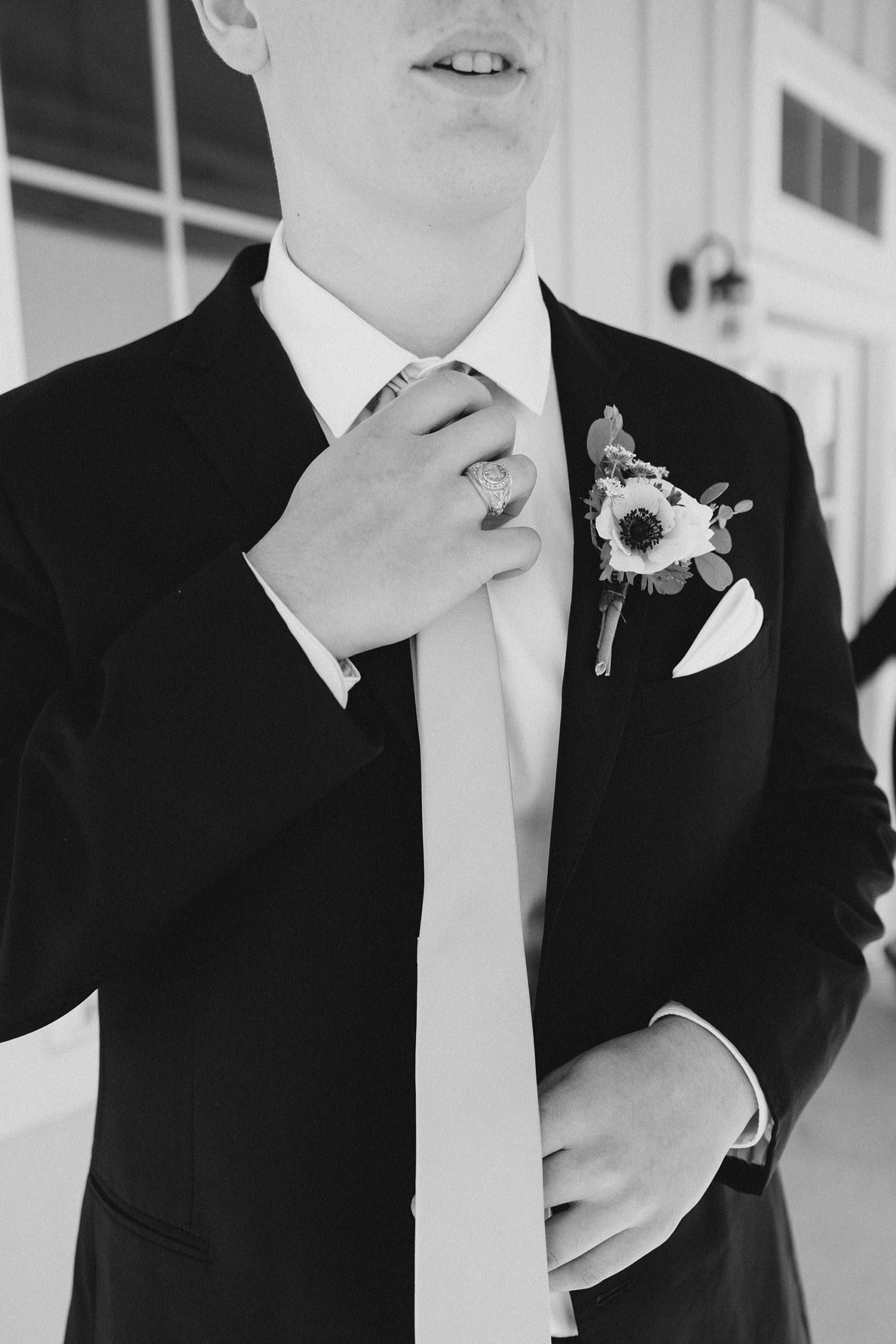groom adjusts tie before spring wedding at The Grand Ivory