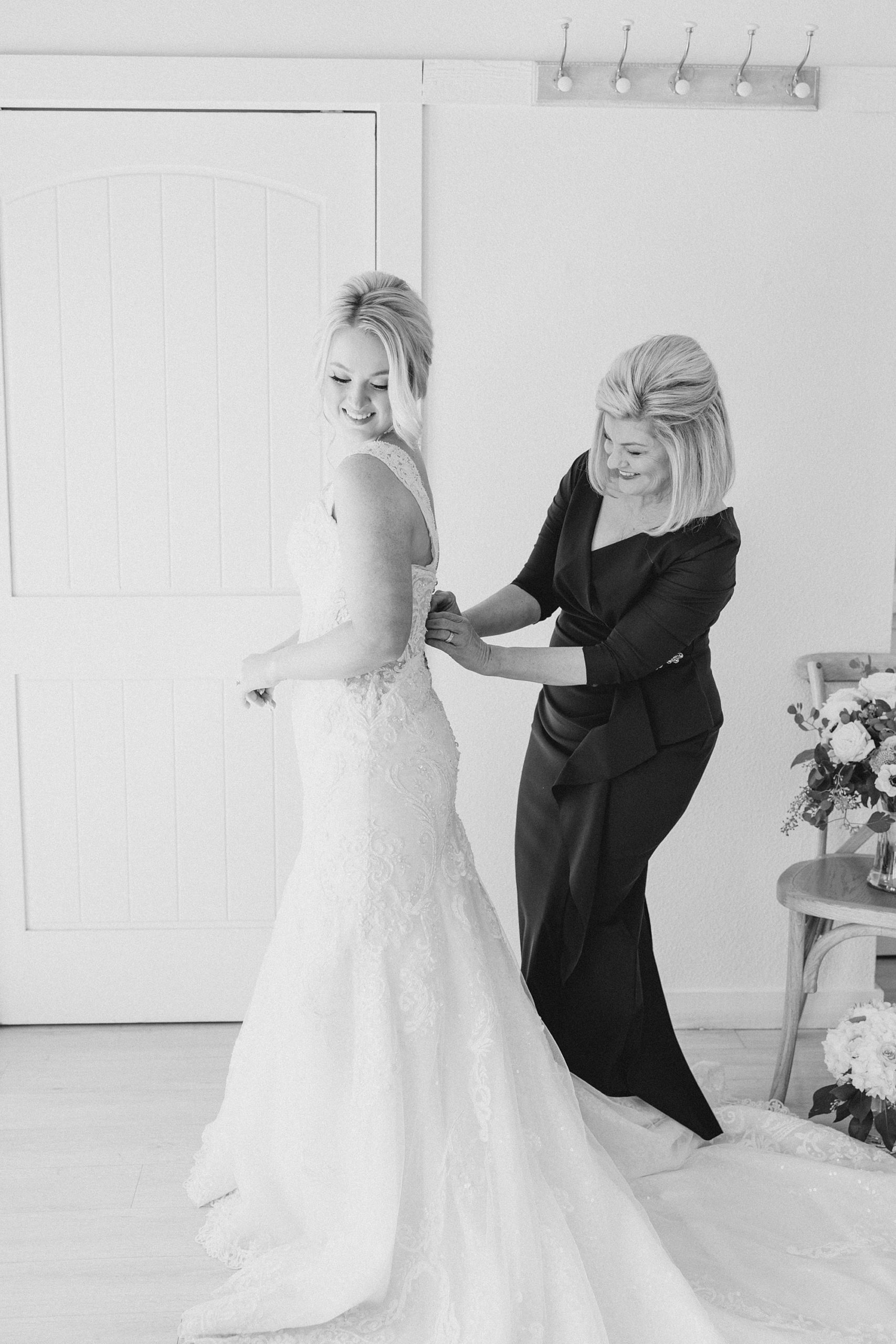 mom helps bride into wedding dress for spring wedding at The Grand Ivory
