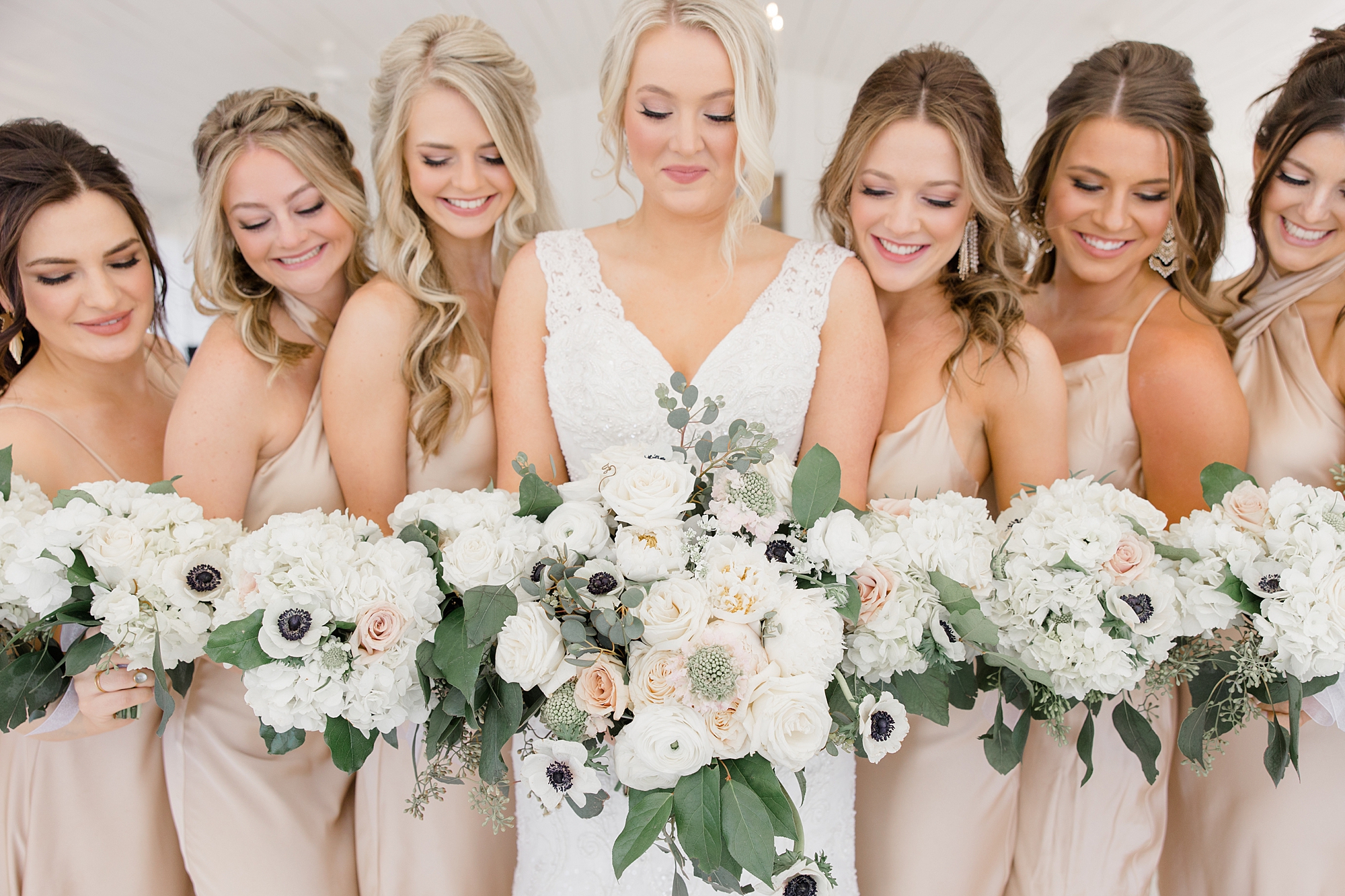 bride and bridesmaids hold all-white bouquets before spring wedding at The Grand Ivory