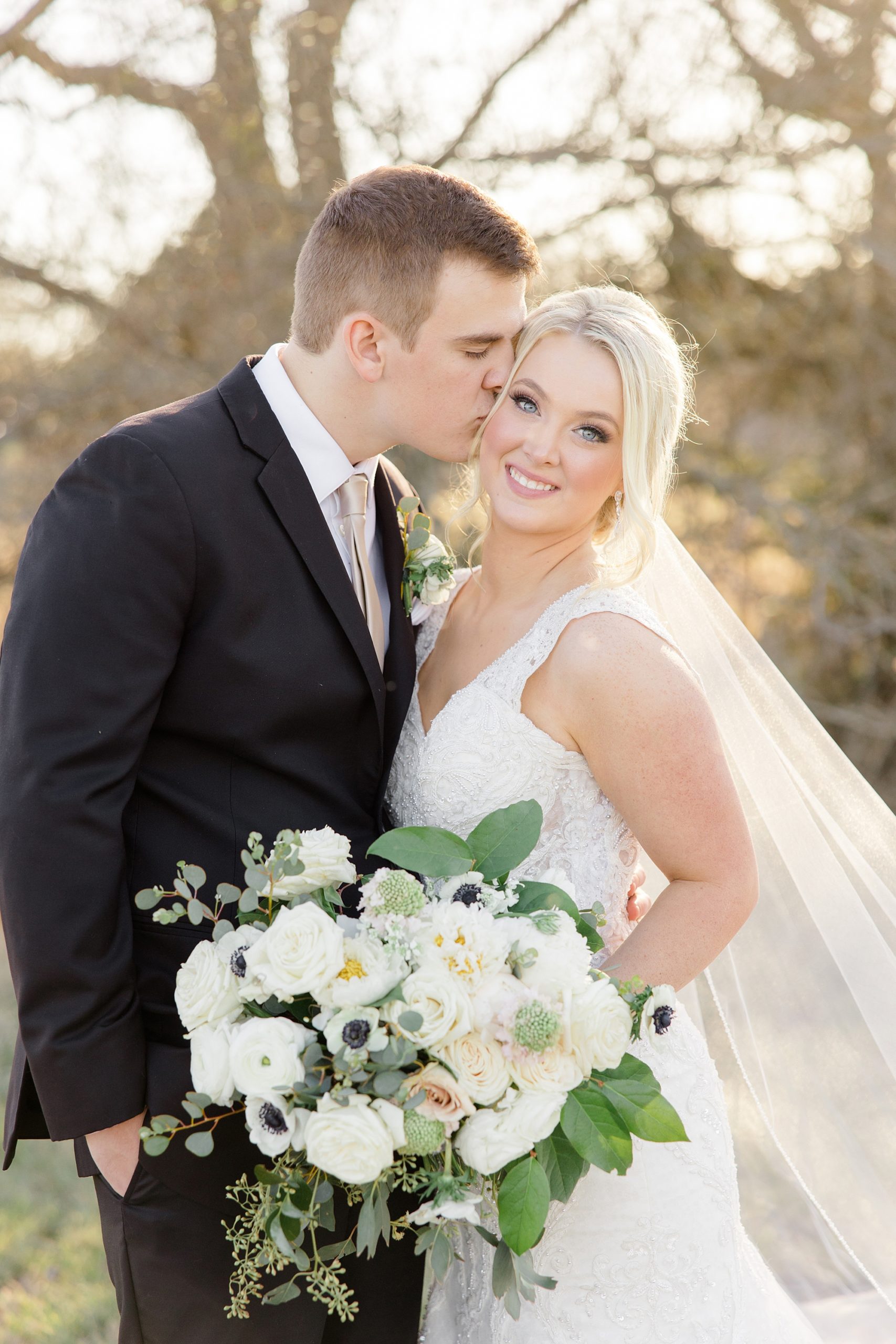 groom kisses bride's cheek during TX wedding portraits 