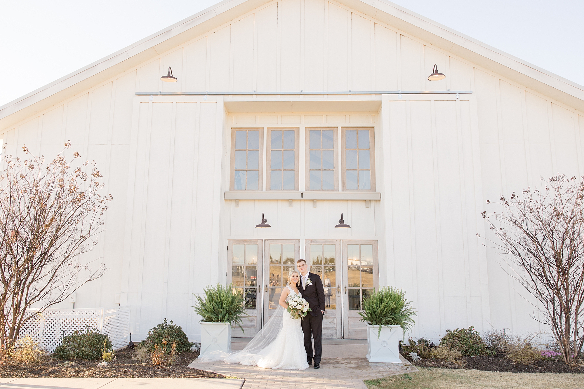 bride and groom hug outside The Grand Ivory barn