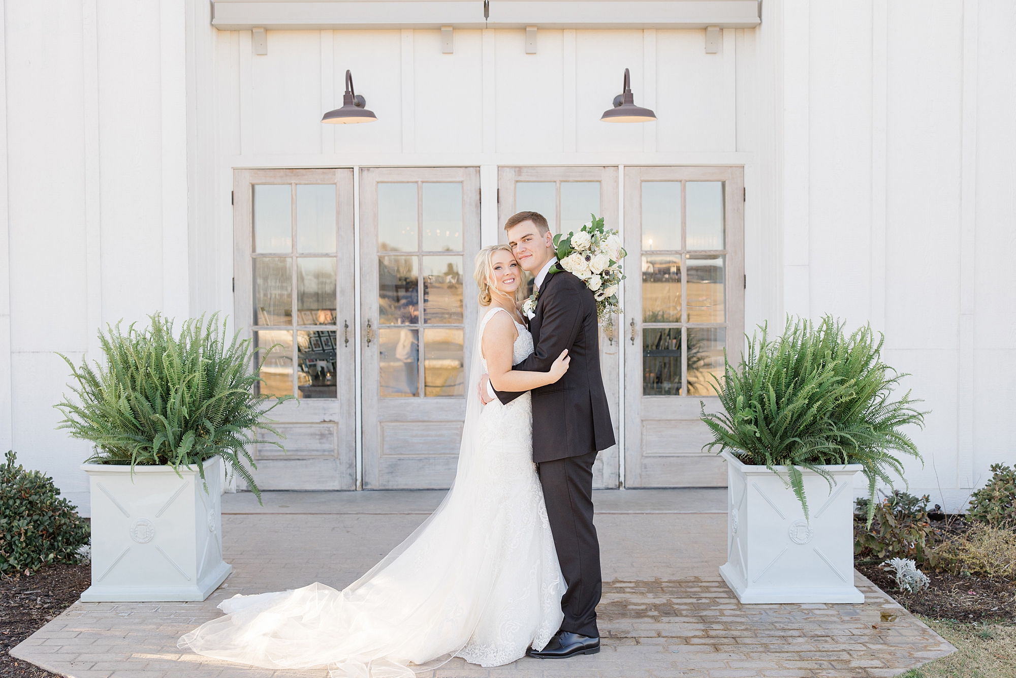 bride and groom hug outside barn doors at  The Grand Ivory