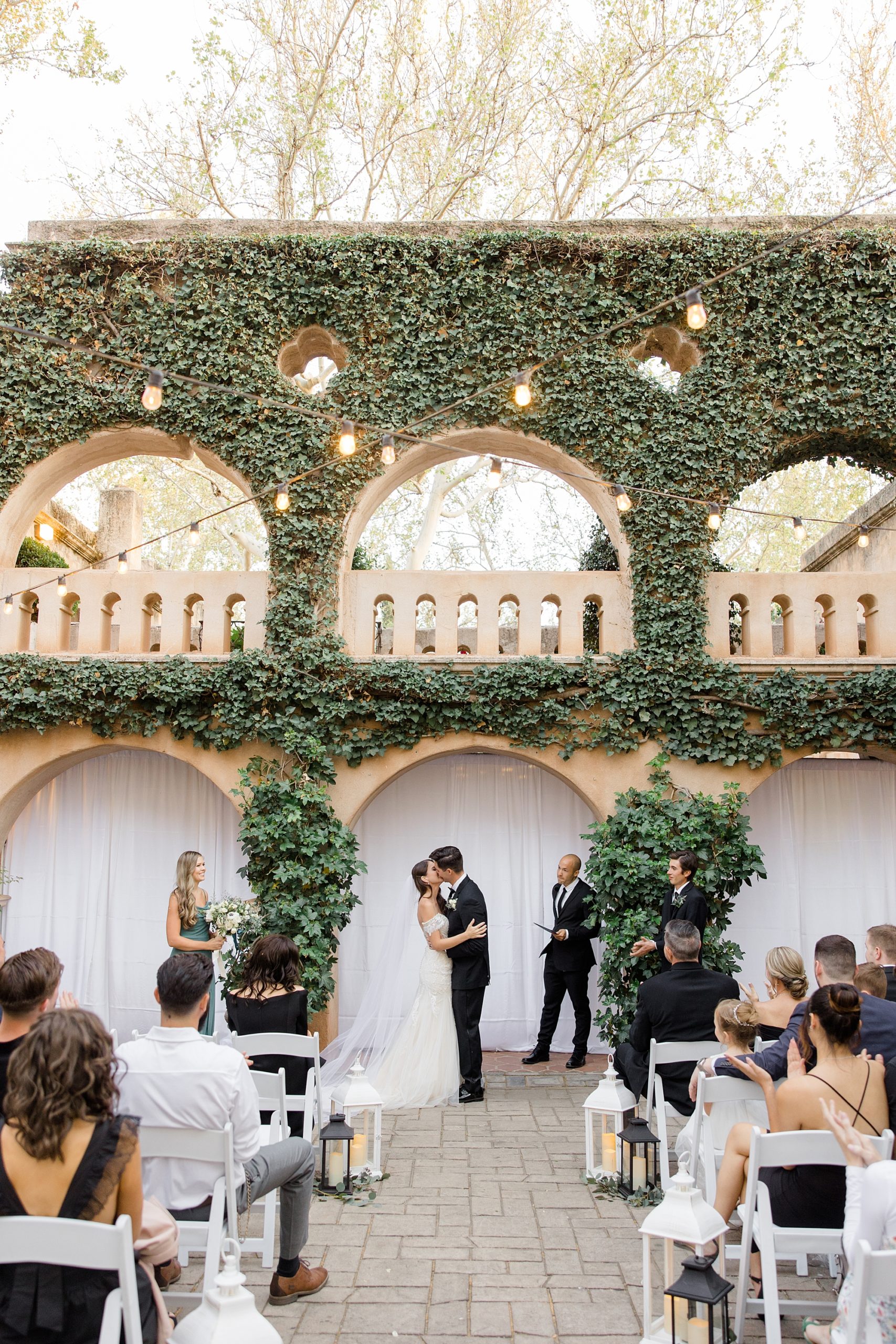 newlyweds kiss under ivy covered archway at Tlaquepaque
