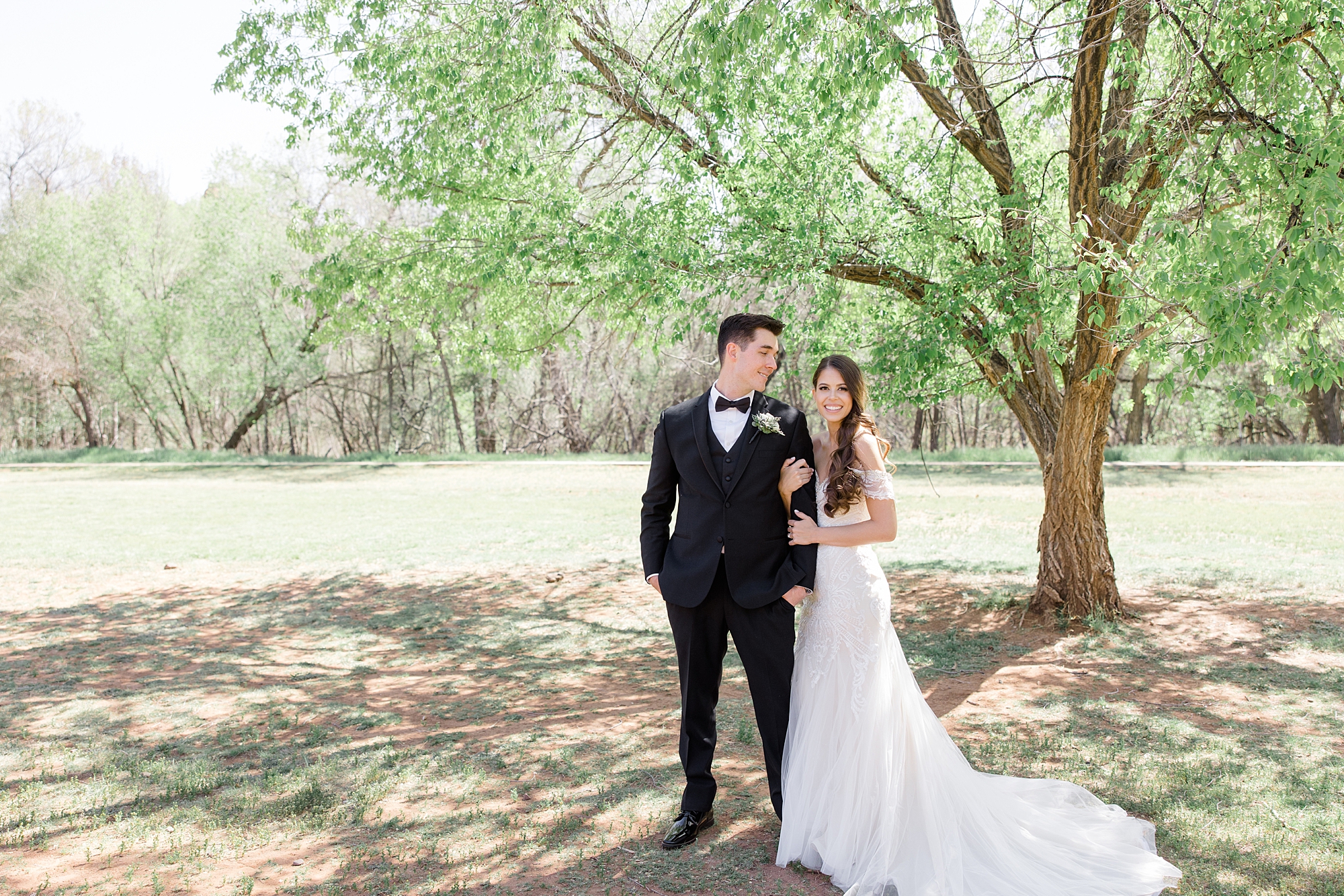 bride and groom stand together under tree in Arizona 