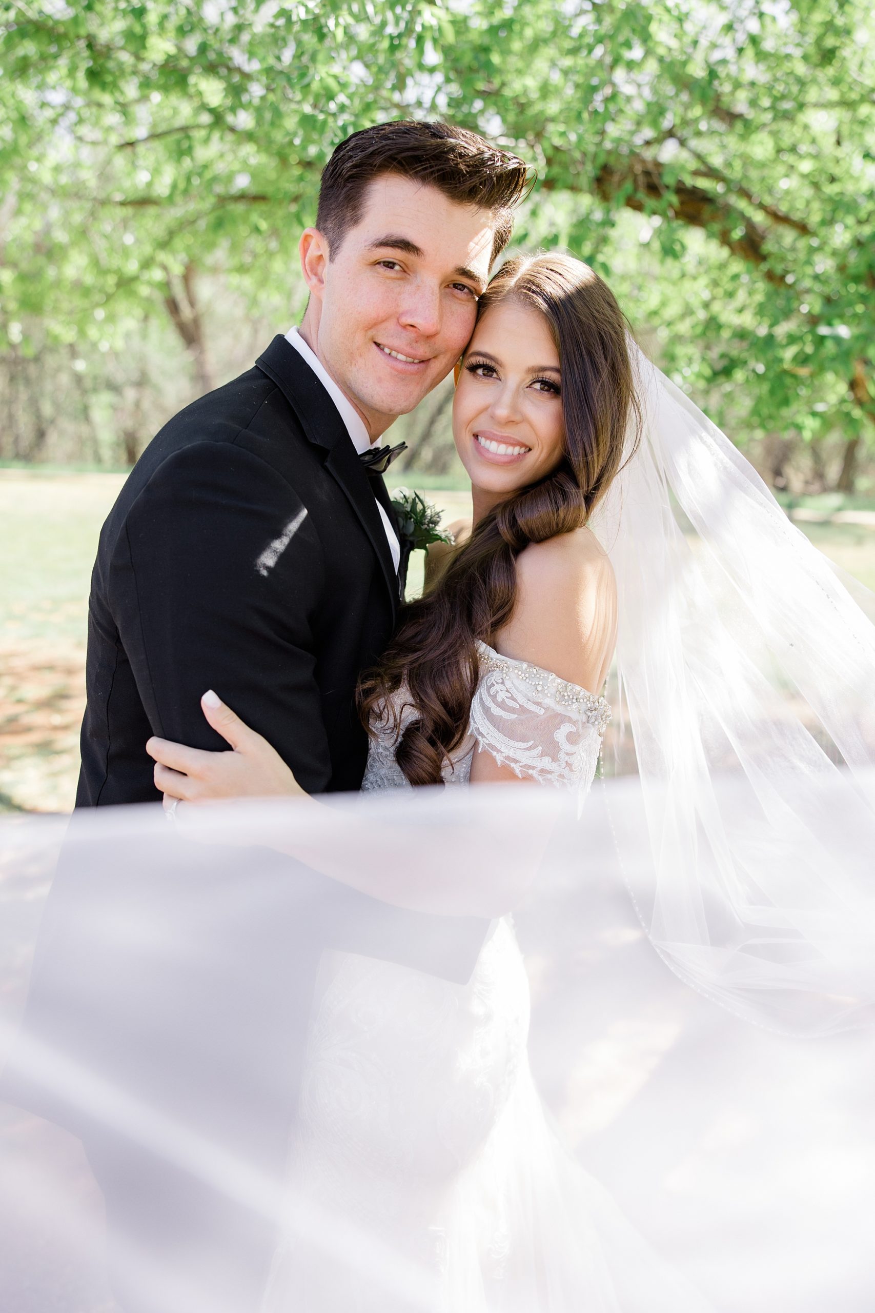 bride and groom hug with veil around them