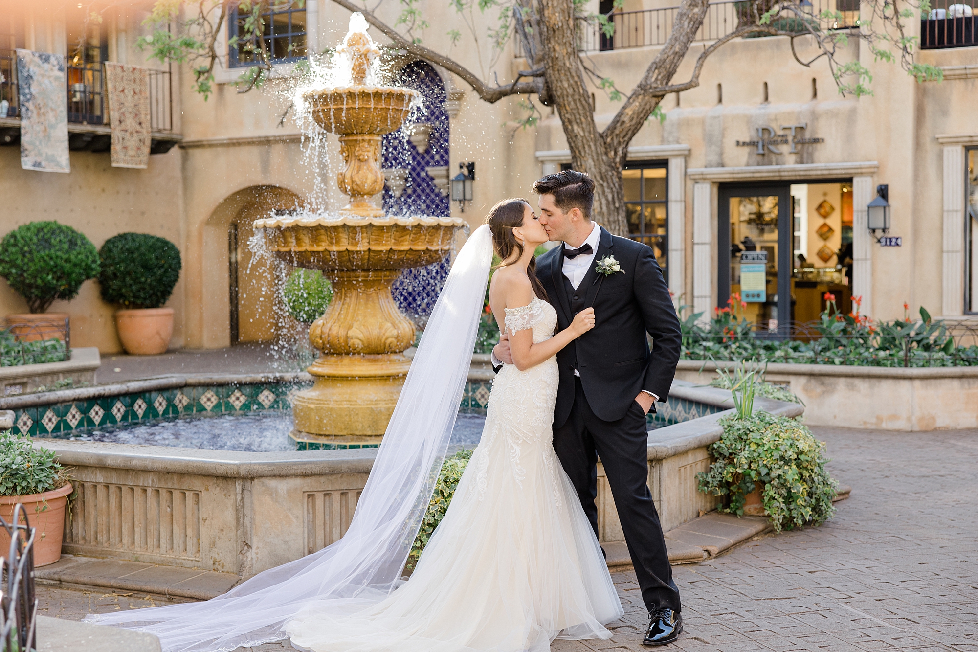 newlyweds kiss by fountain in courtyard at Tlaquepaque