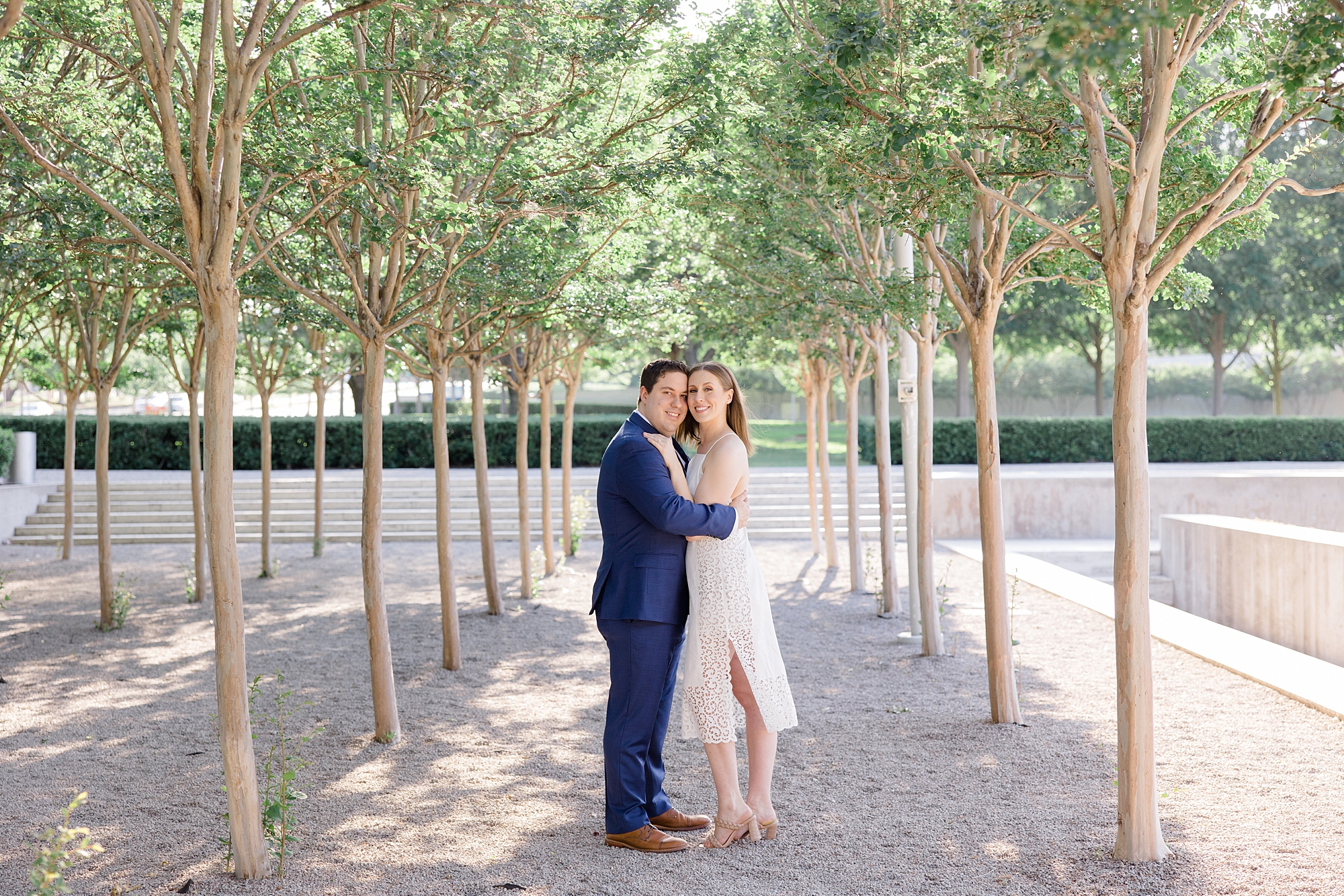Texas couple hugs under trees during engagement photos at Kimball Art Center
