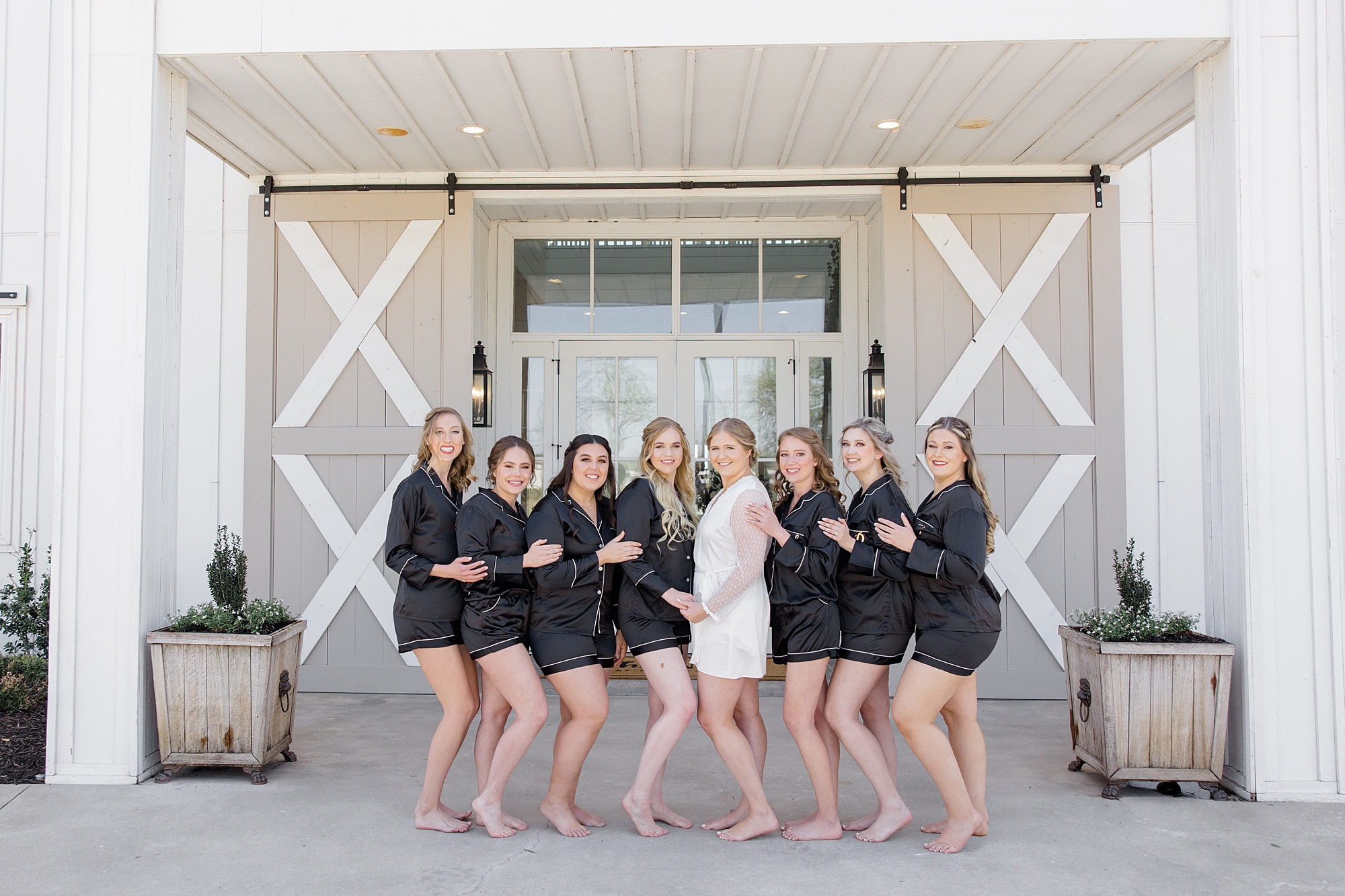 bride and bridesmaids pose outside the Nest at Ruth Farms in matching pajamas