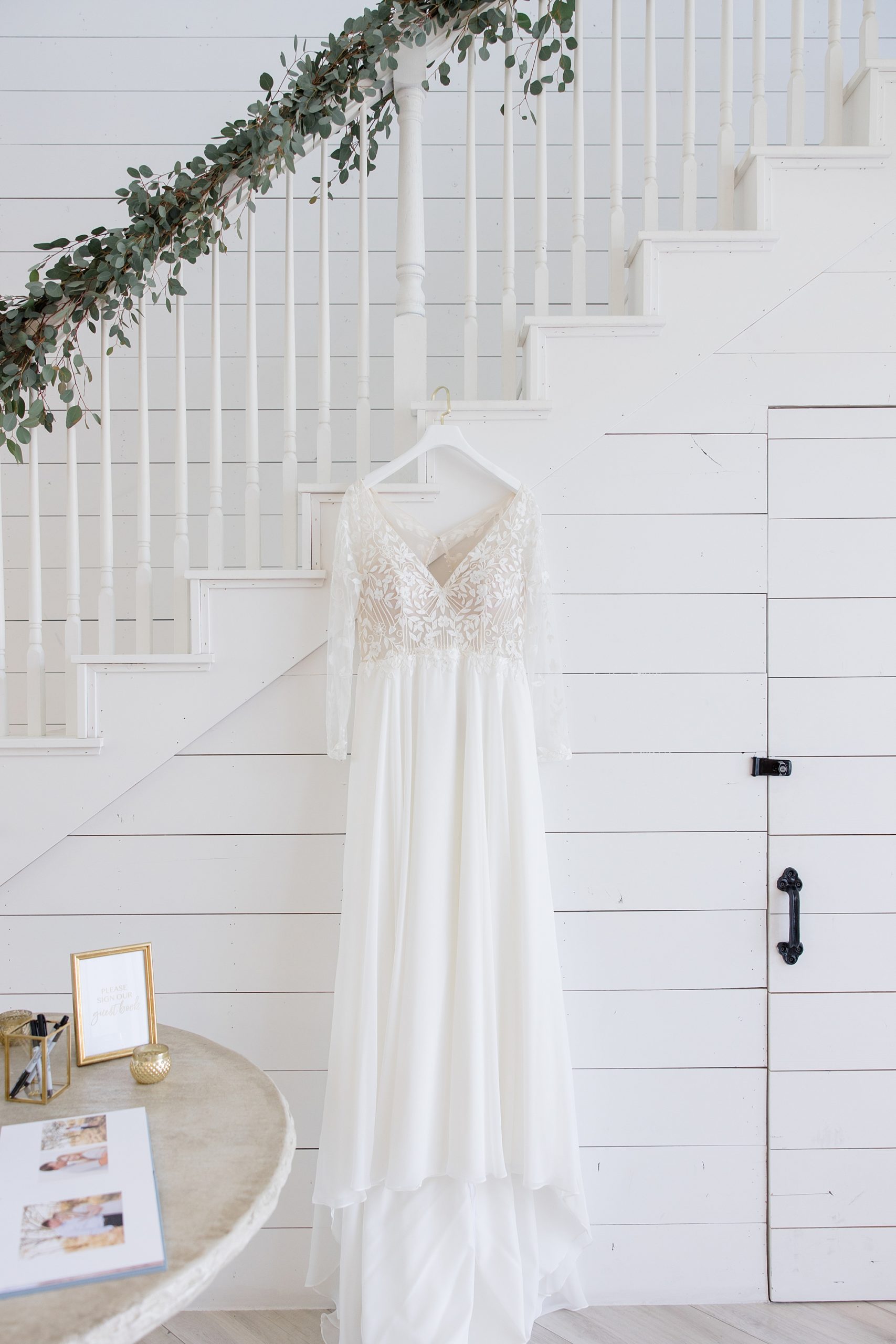 wedding dress hangs on staircase of The Nest at Ruth Farms