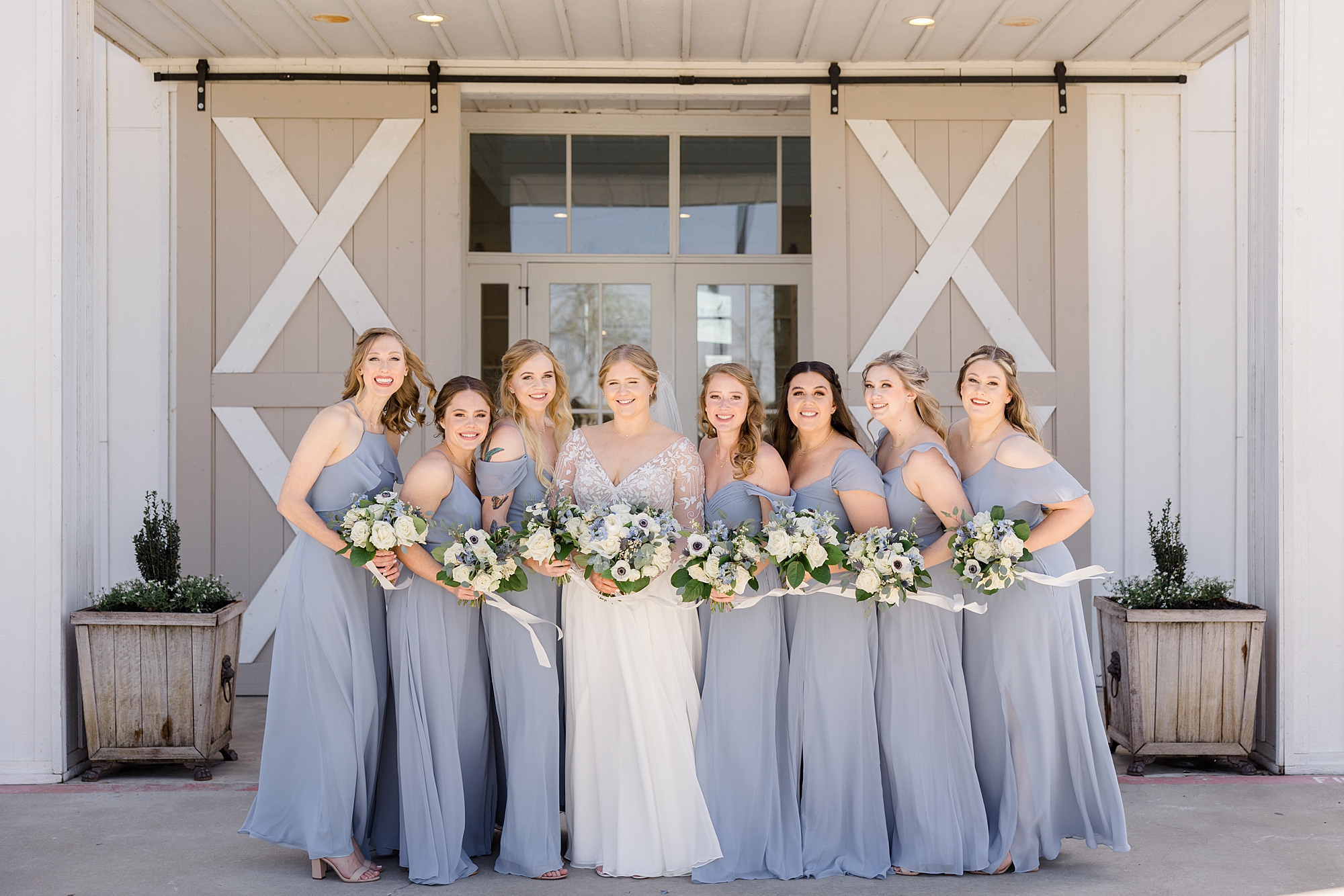 bride stands with bridesmaids in light blue gowns for spring wedding at the Nest at Ruth Farms