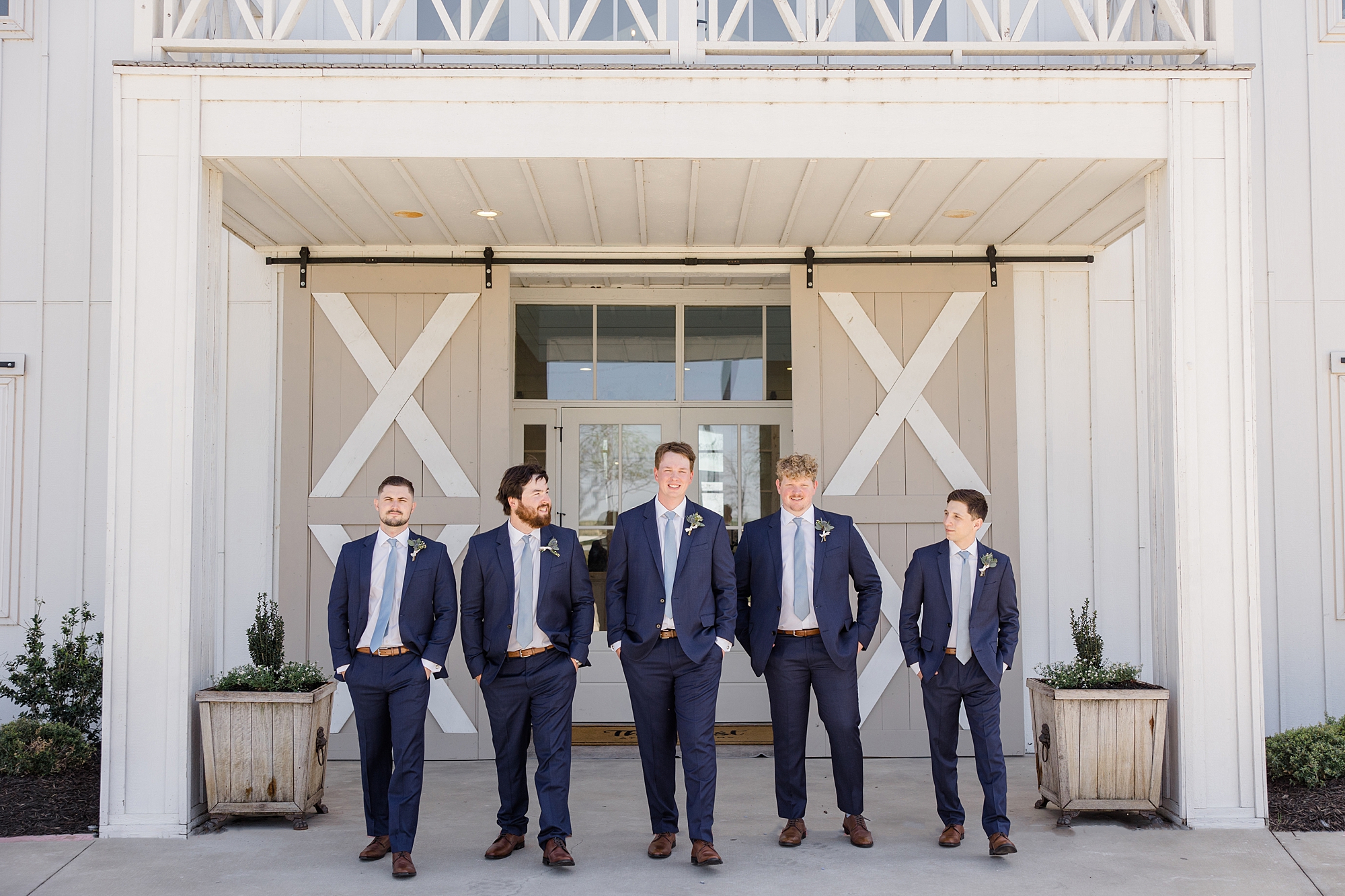 groomsmen walk in front of barn at the Nest at Ruth Farms