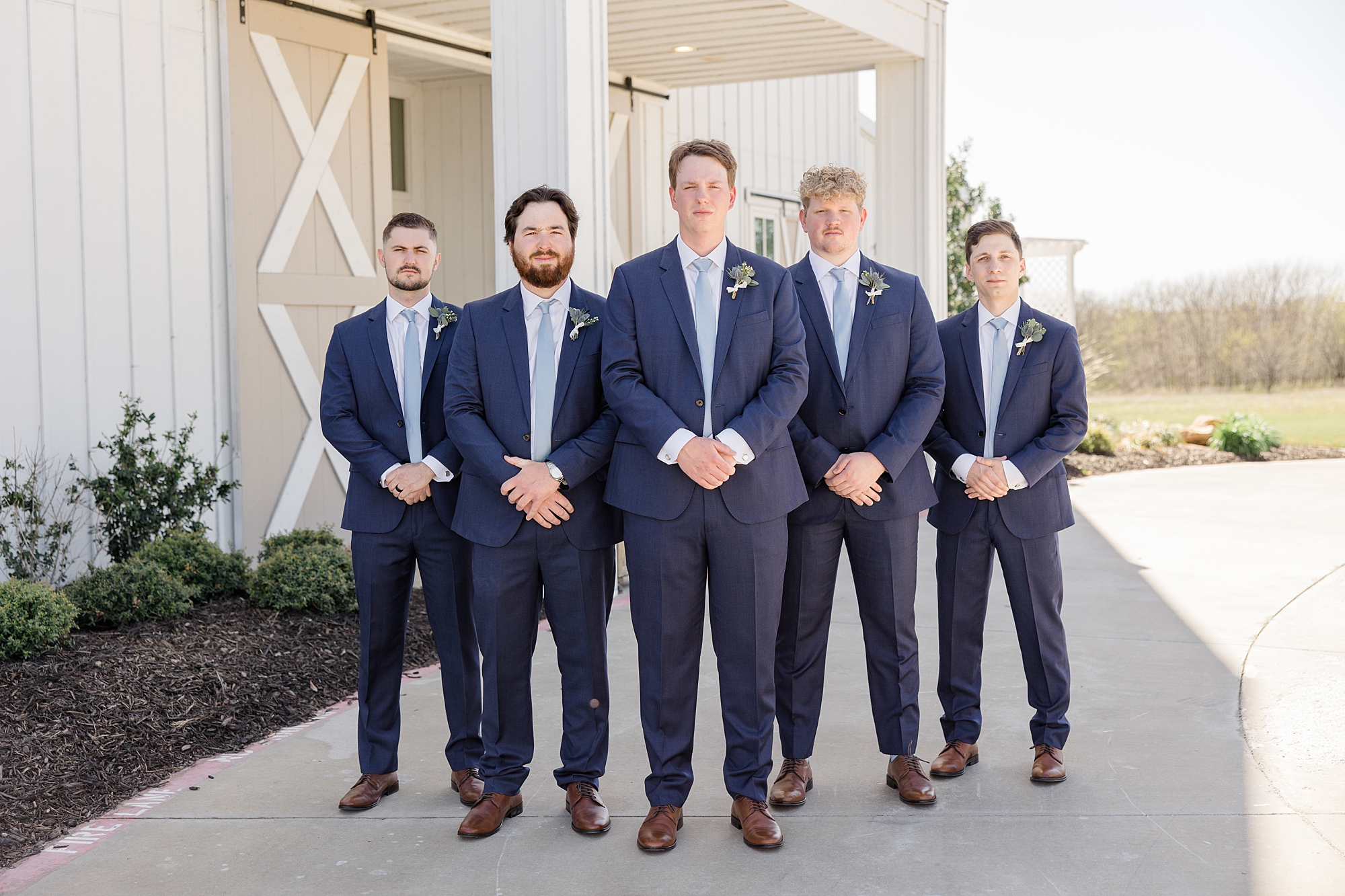 groom stands with groomsmen in navy suits before spring wedding day 