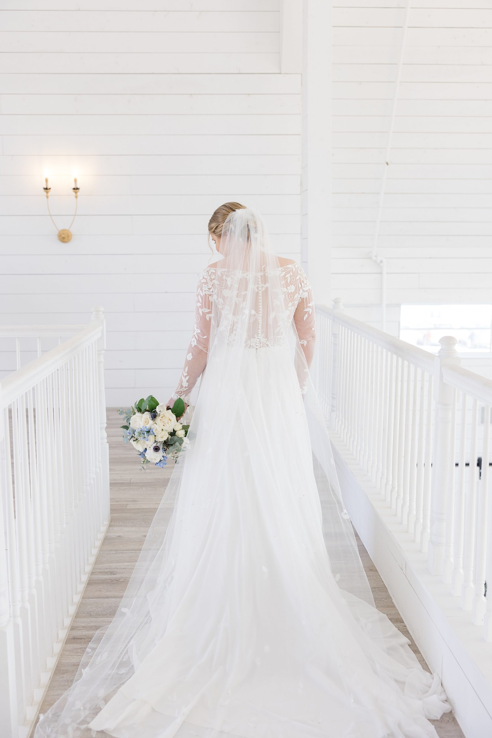 bride holds bouquet and walks across walkway inside the Nest at Ruth Farms