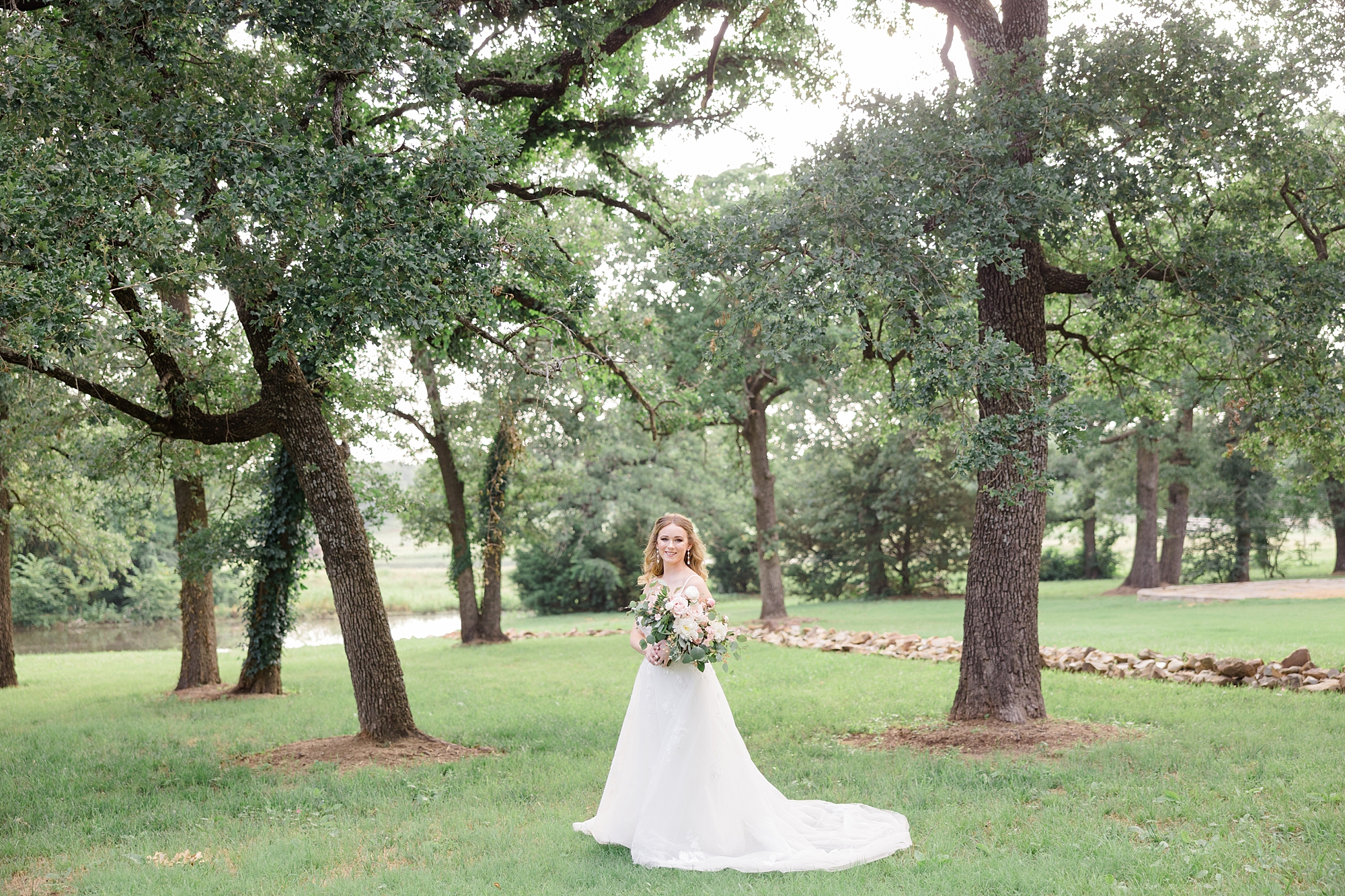 bride poses among trees during Oak and Ivy bridal portraits