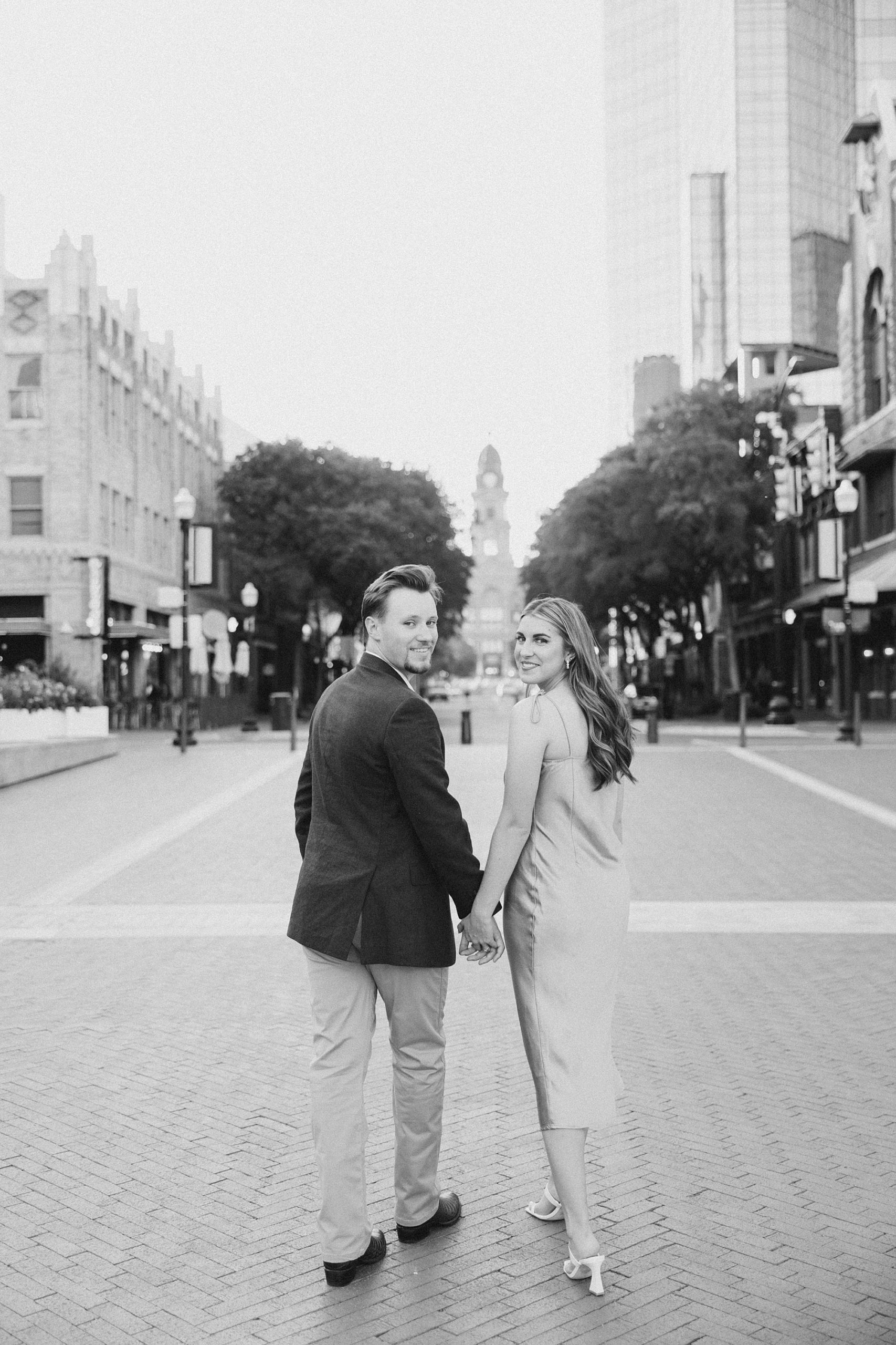 engaged couple holds hands walking through Sundance Square