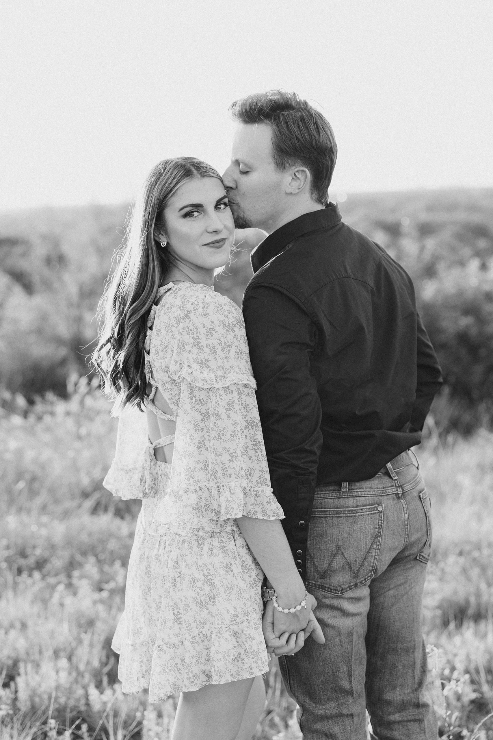 groom kisses fiancee's forehead during engagement session in Fort Worth TX