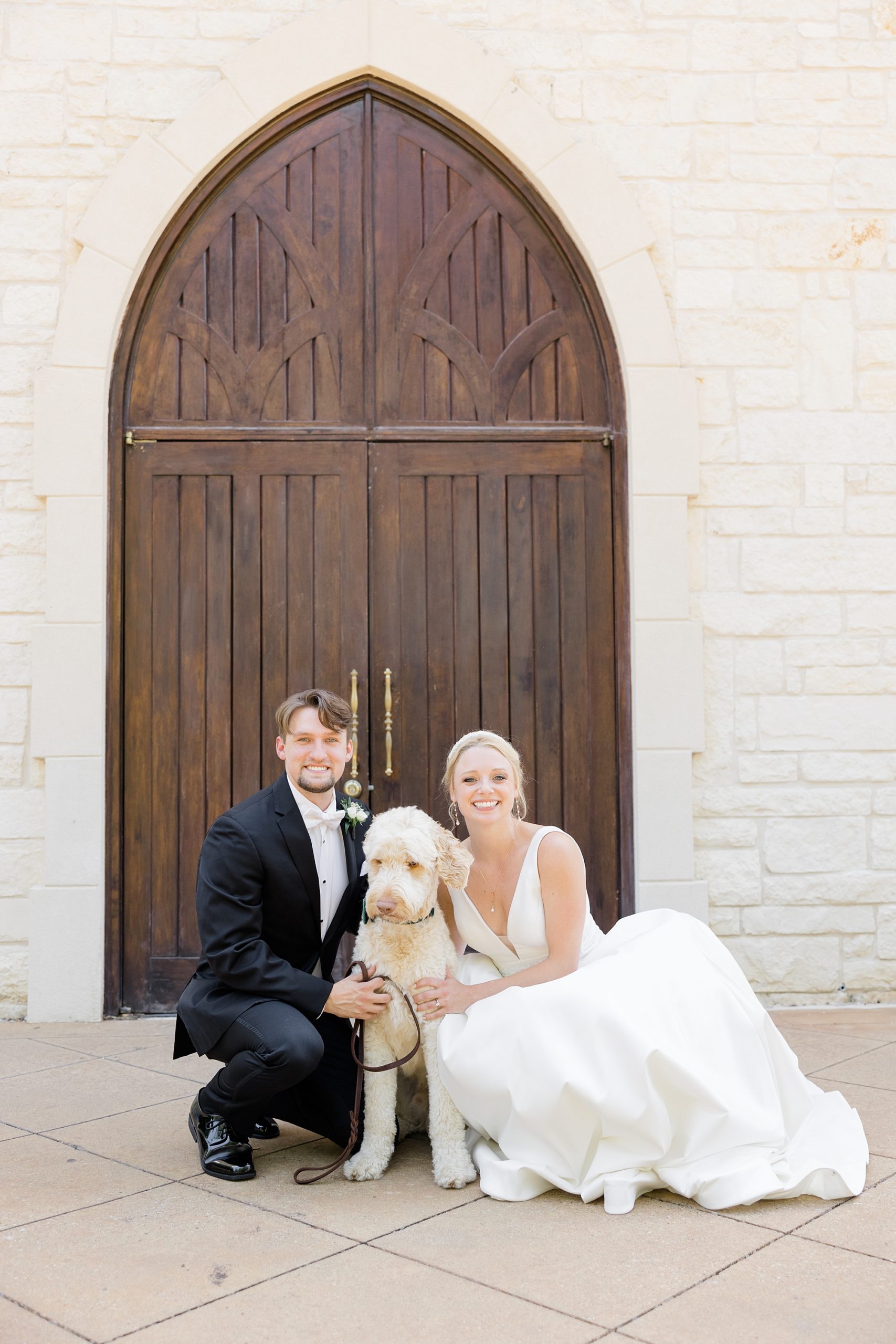 bride and groom sit with dog by wooden doors at Ashton Gardens