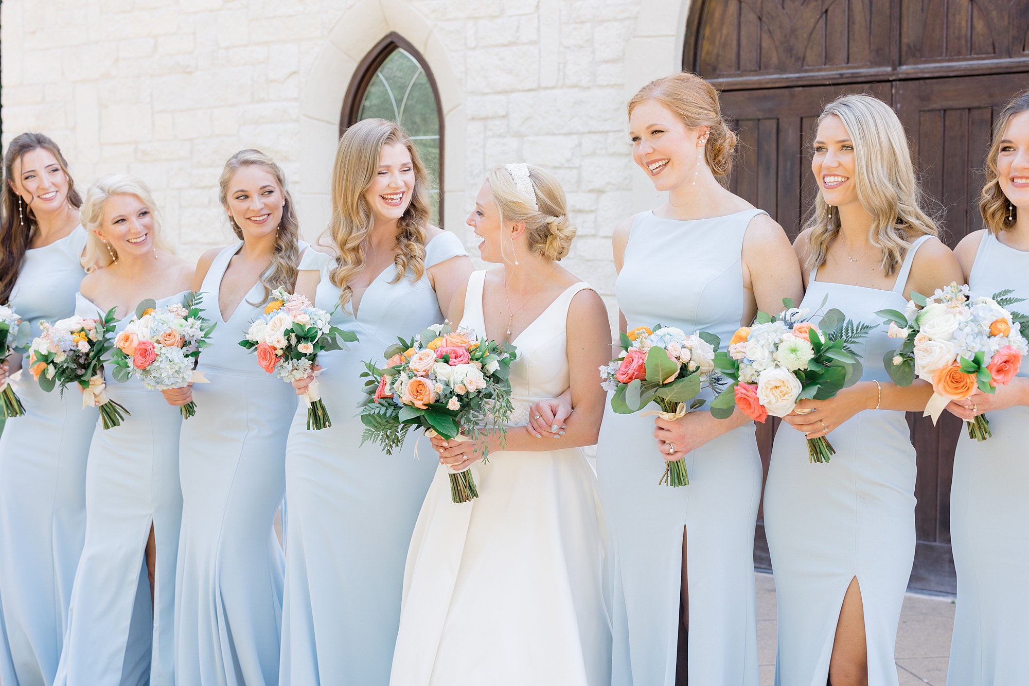 bride looks at bridesmaids in blue gowns