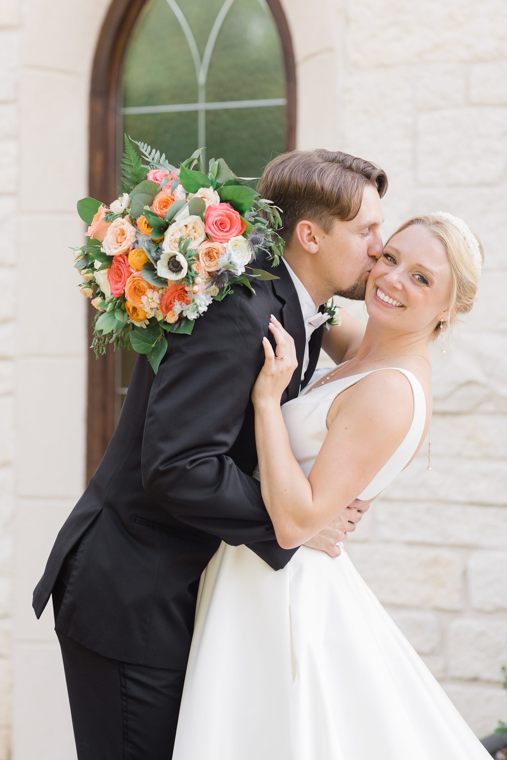 groom leans into bride's cheek kissing her