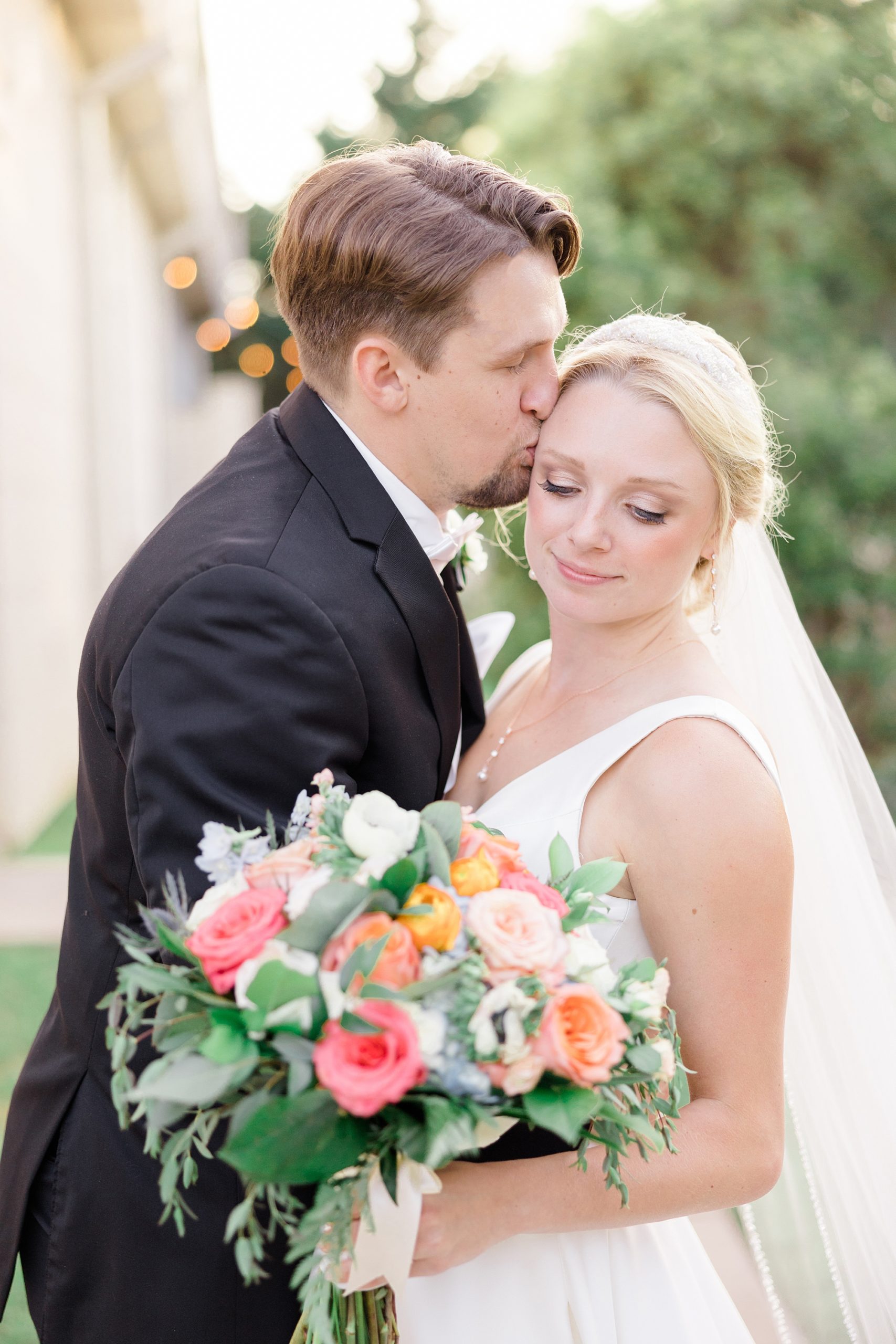 groom kisses bride's forehead during sunset photos at Ashton Gardens