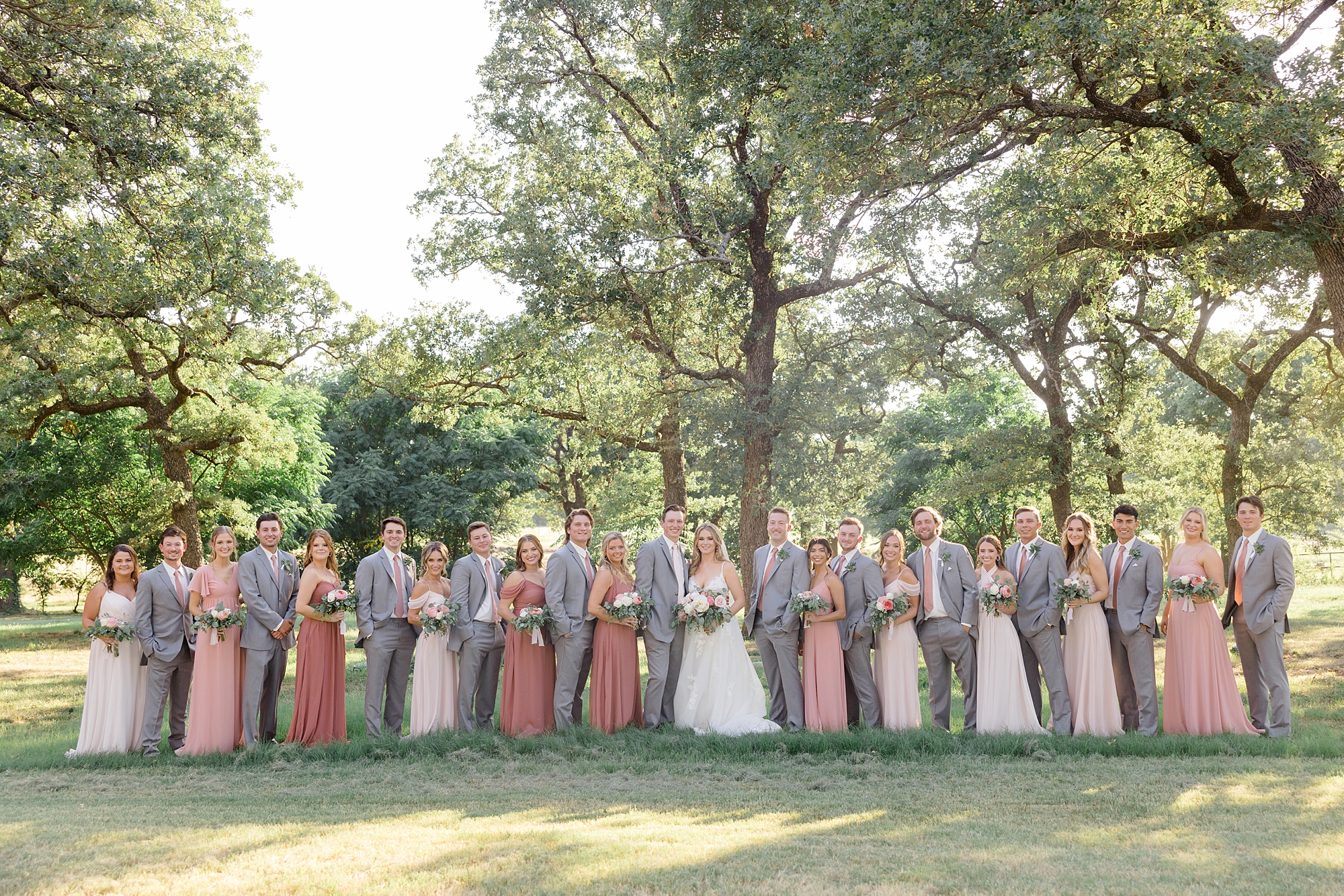 newlyweds pose with wedding party in grey and coral