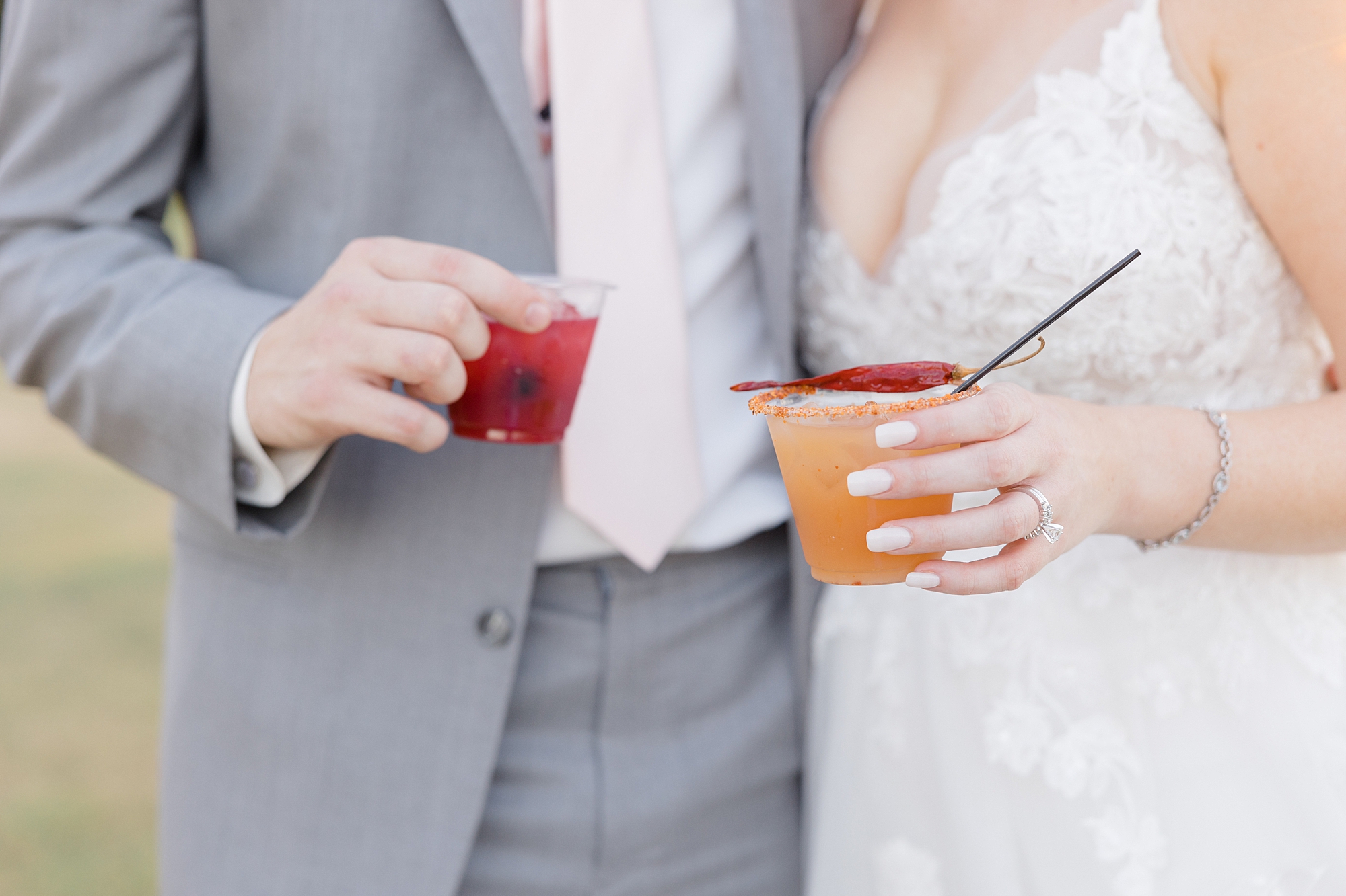 bride and groom hold cocktails from summer wedding
