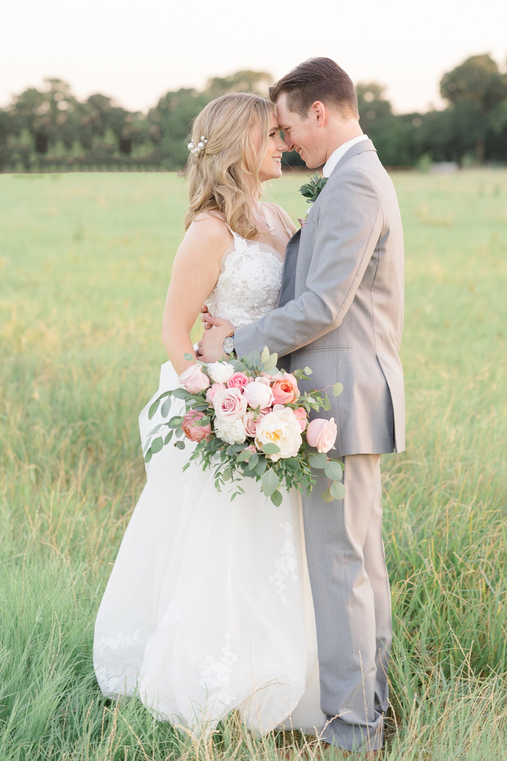bride and groom hug in field at Oak + Ivy
