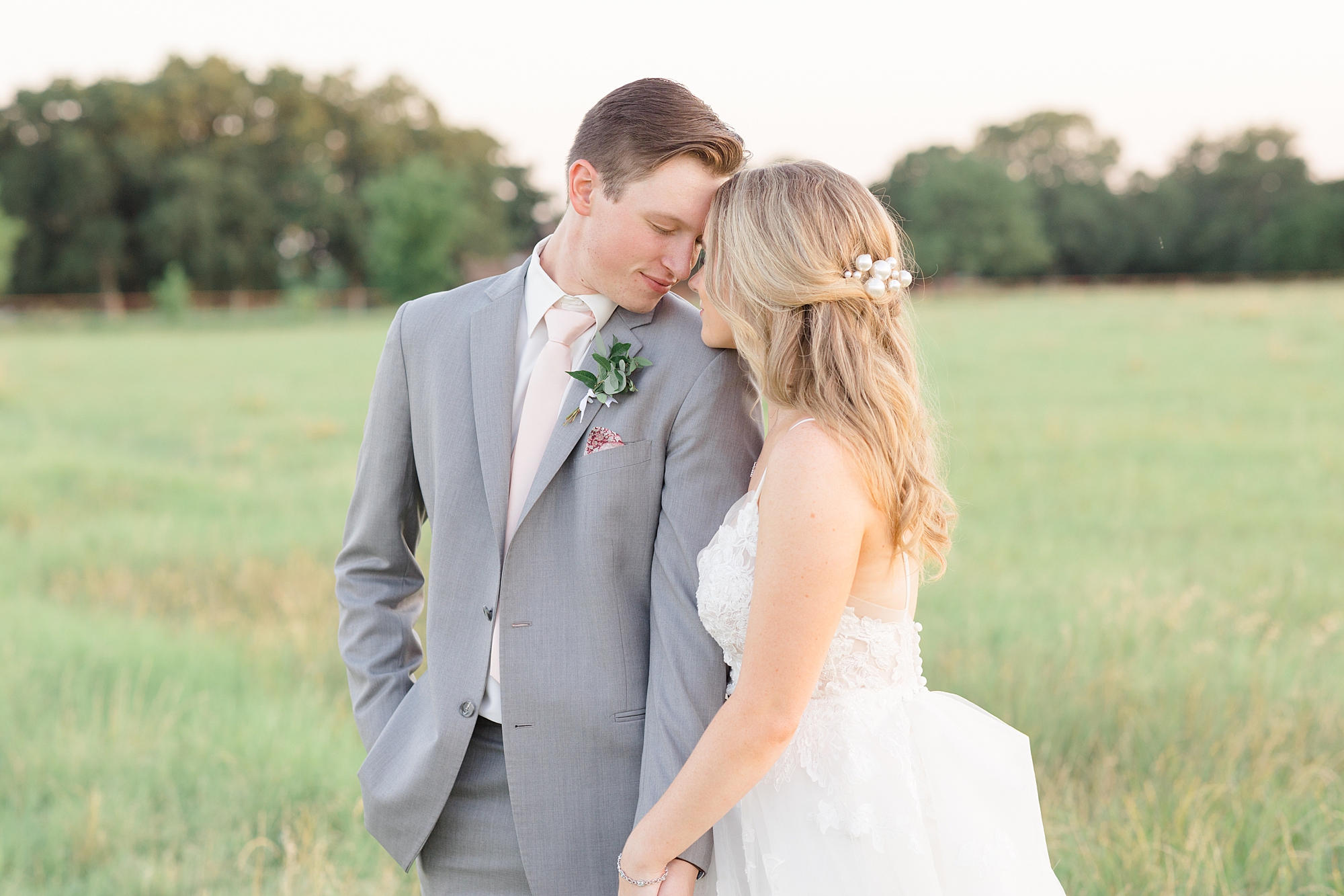 newlyweds lean heads together during Oak + Ivy summer wedding portraits 