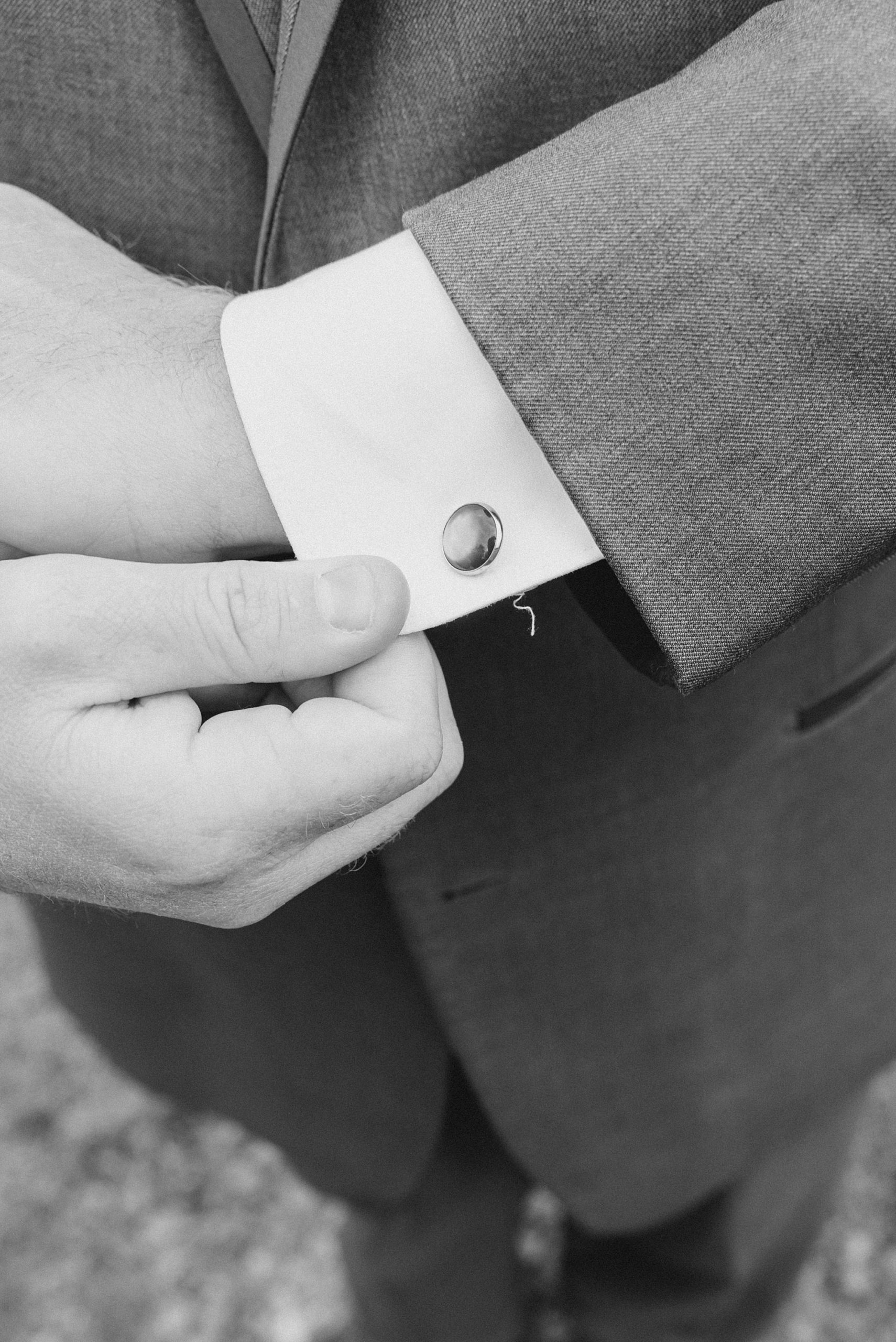 groom adjusts cufflinks for Barn at Stoney Creek wedding