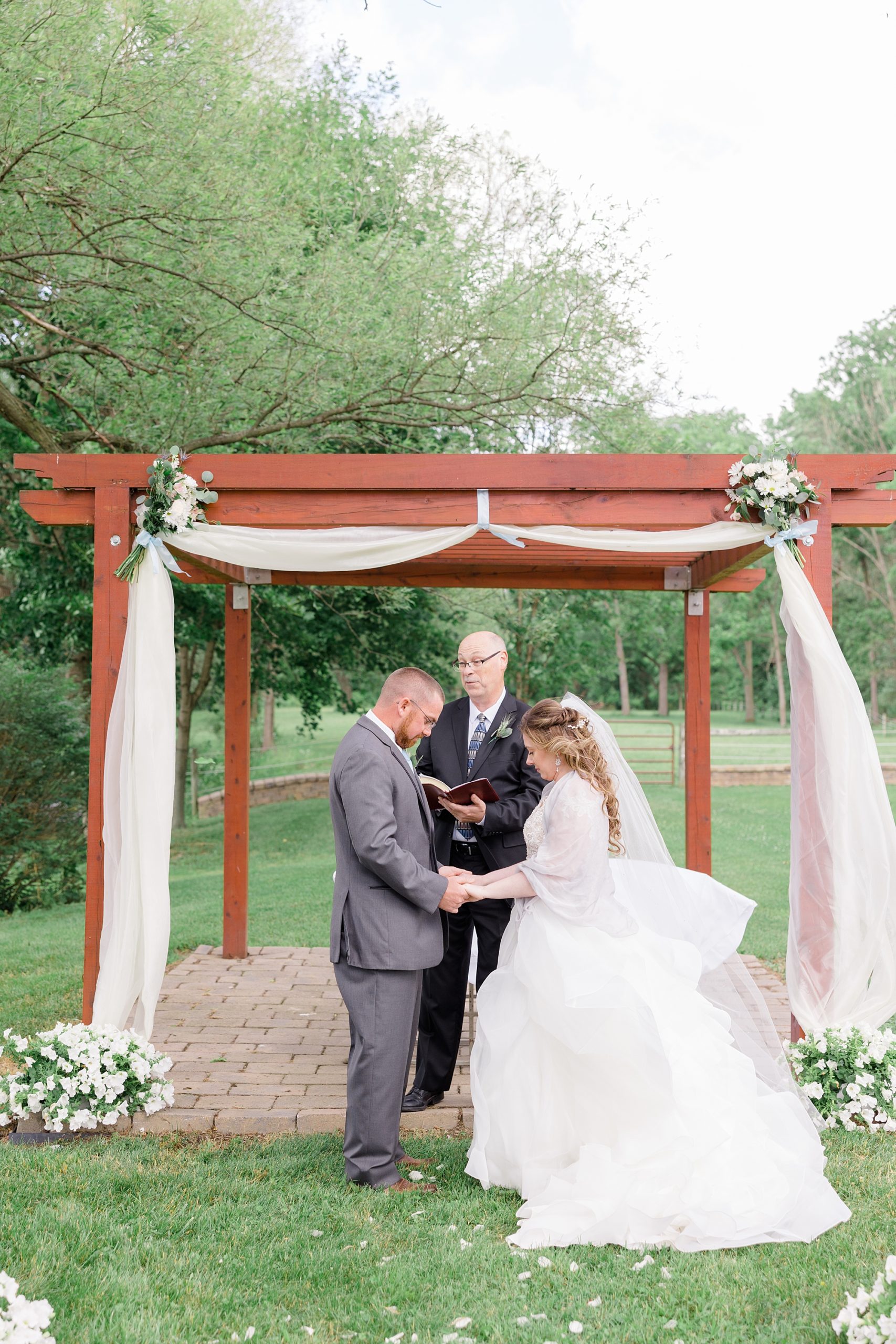 bride and groom hold hands during rustic outdoor ceremony