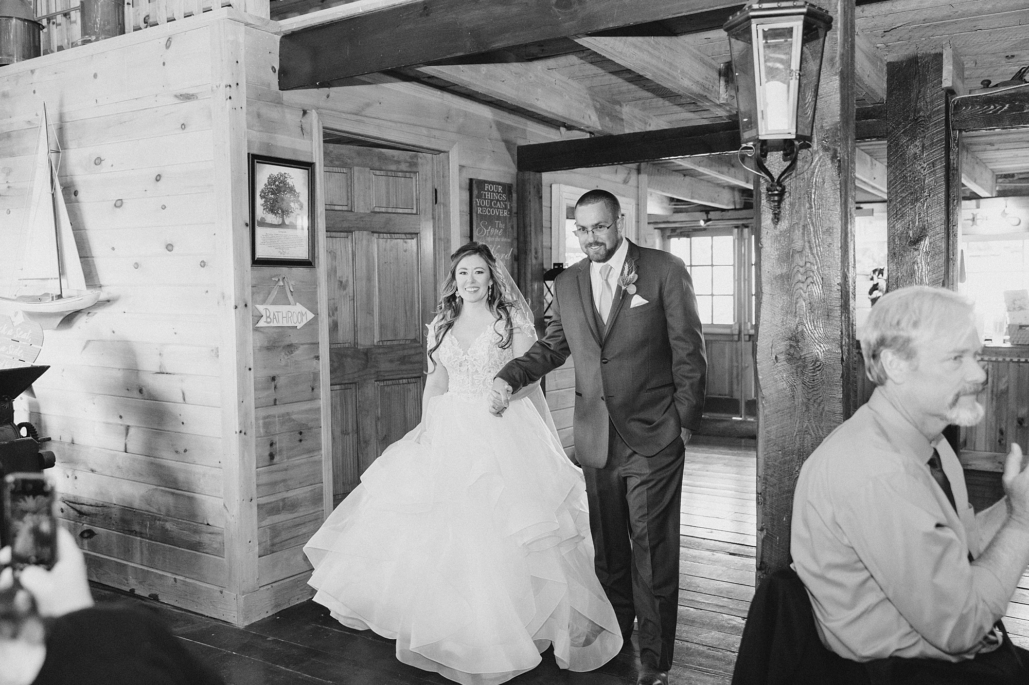bride and groom smile walking into rustic New York wedding reception