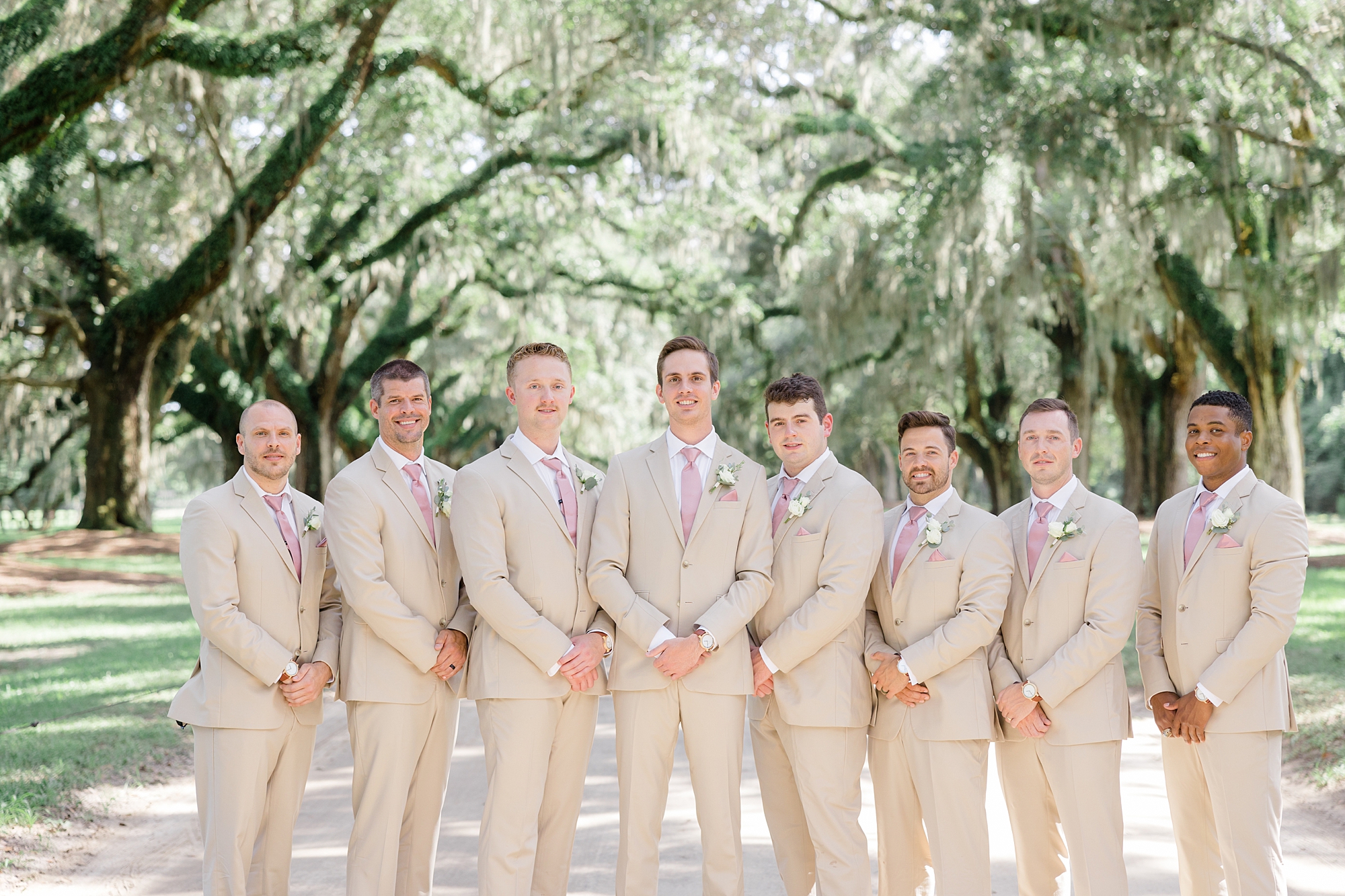 groom and groomsmen stand under oak trees at Boone Hall
