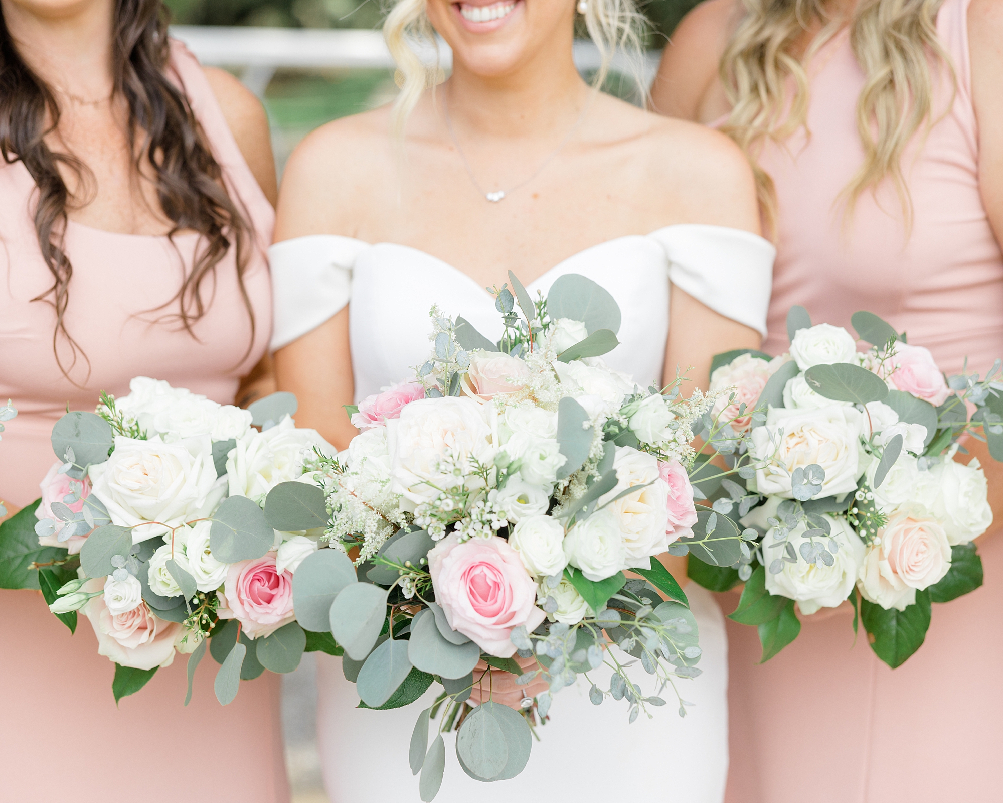 bride holds bouquet of pink and white flowers in off-the-shoulder wedding gown at Boone Hall