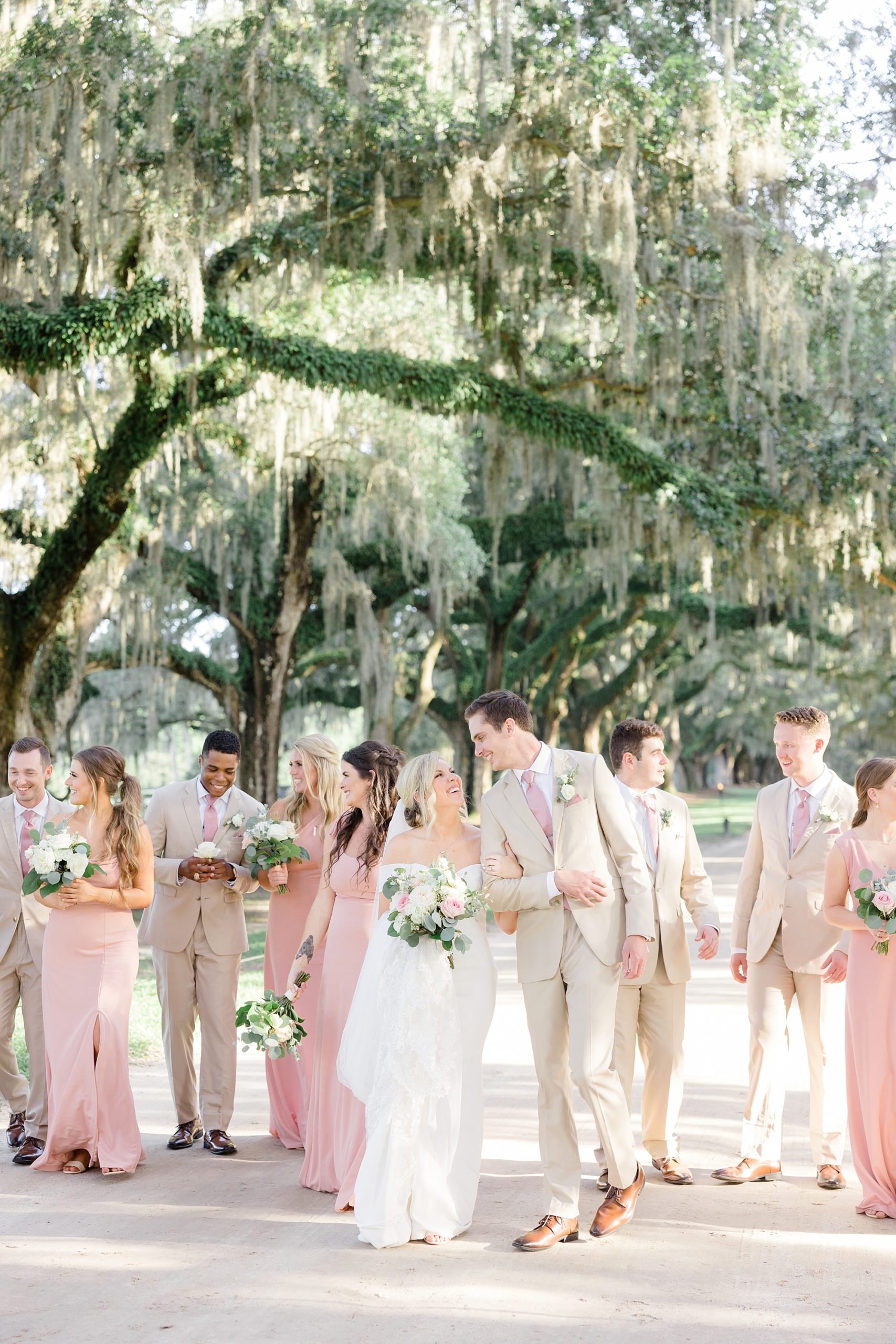 bride and groom walk with wedding party on driveway at Boone Hall