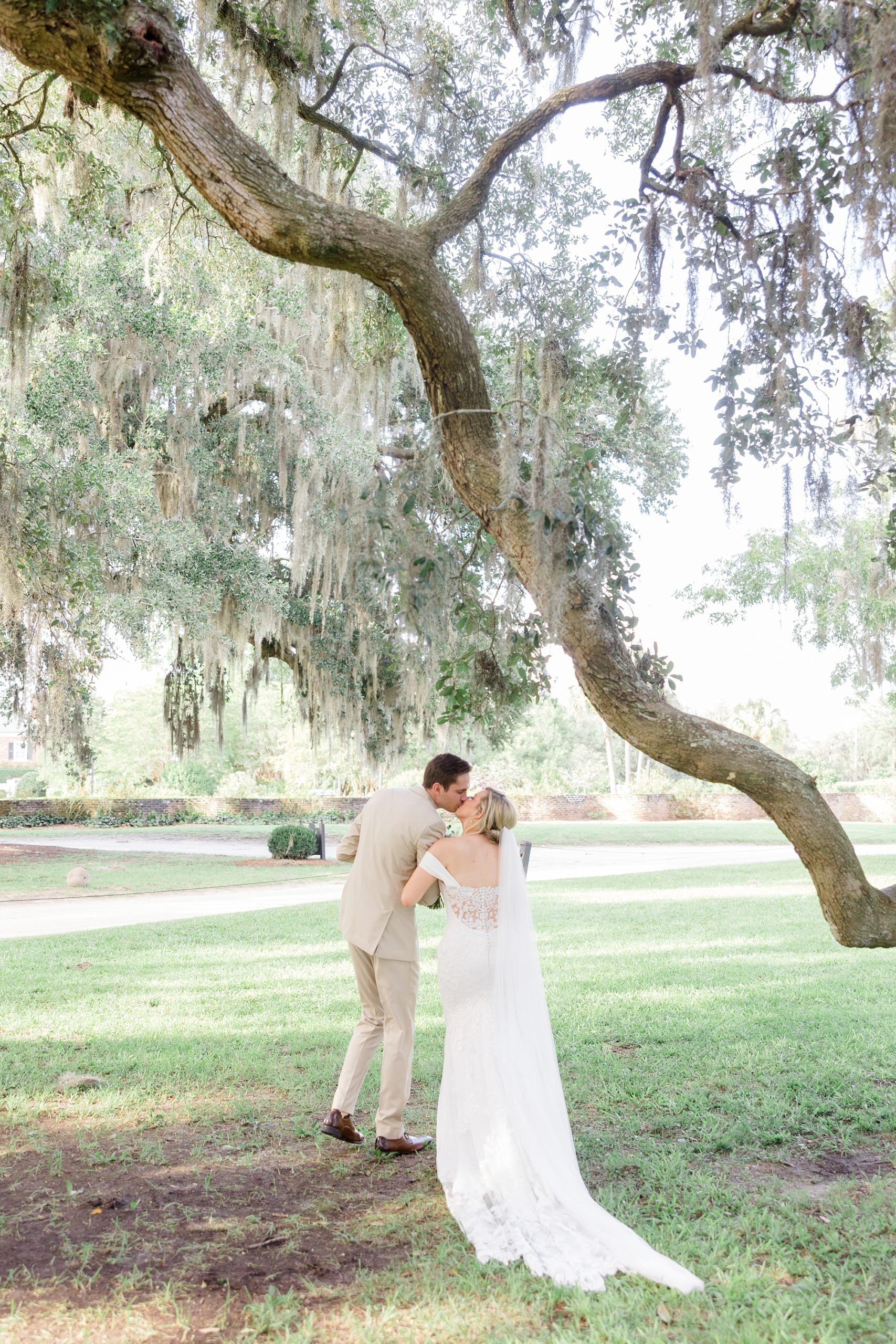 bride and groom kiss under oak tree at Boone Hall