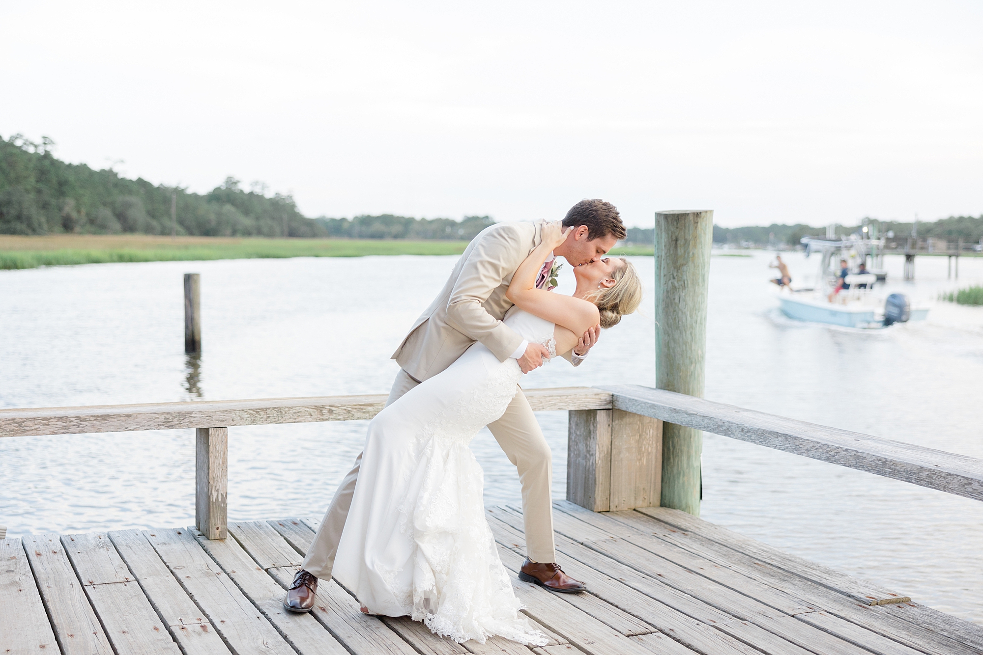 groom dips bride along waterfront at Boone Hall