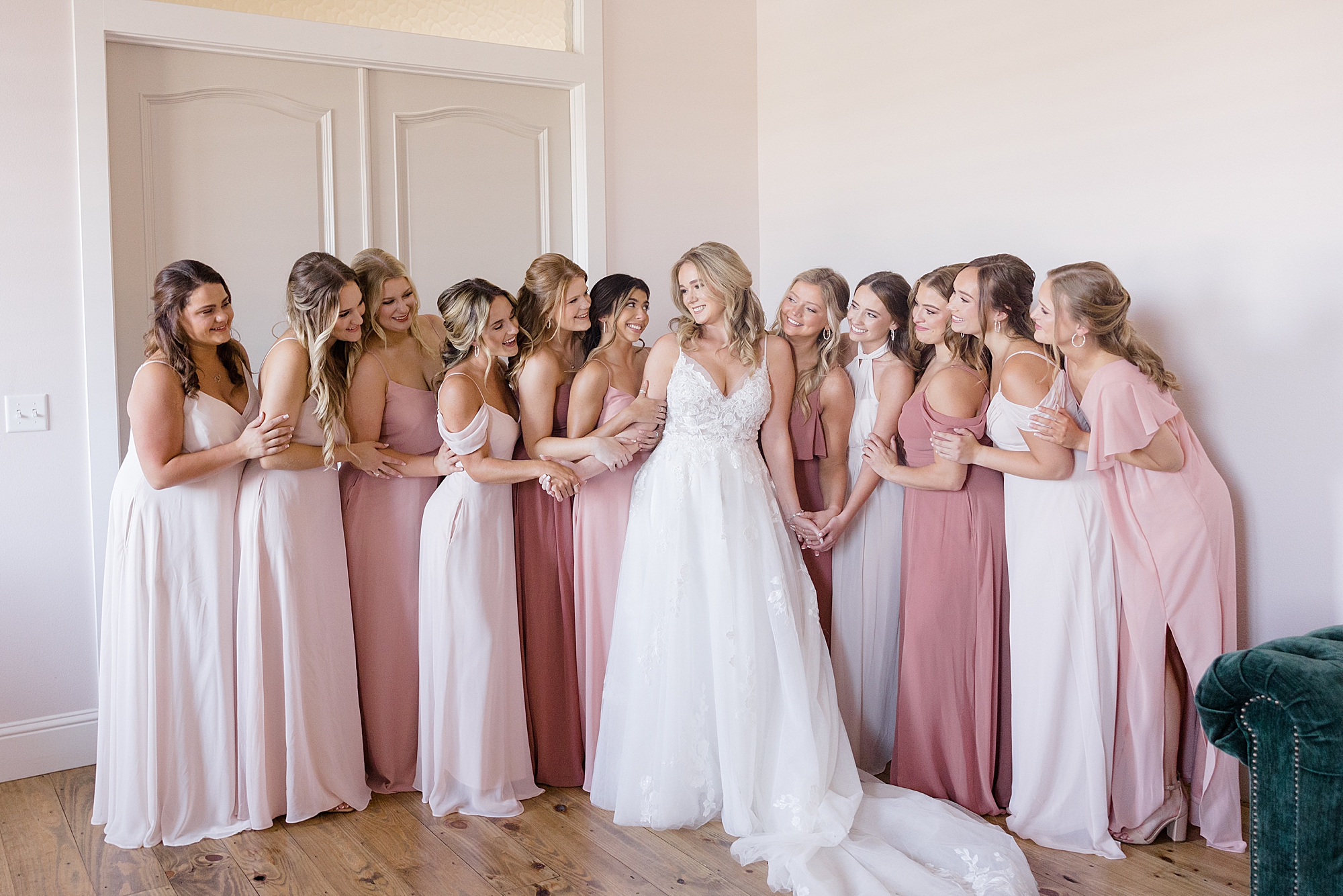 bride hugs bridesmaids in pink gowns at Oak + Ivy