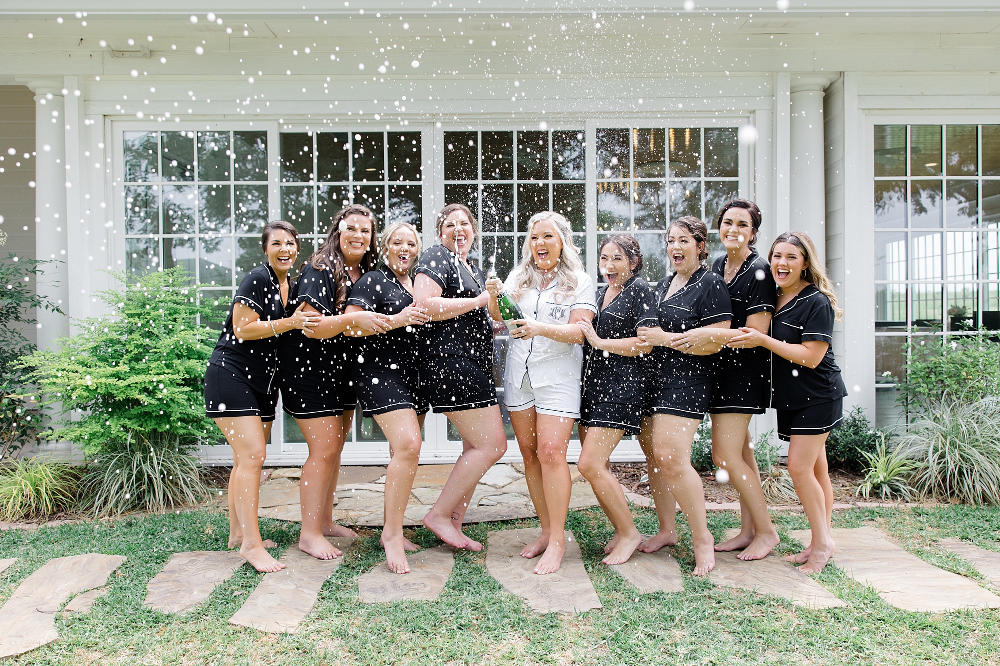 bride pops champagne with bridesmaids in matching black pajamas 